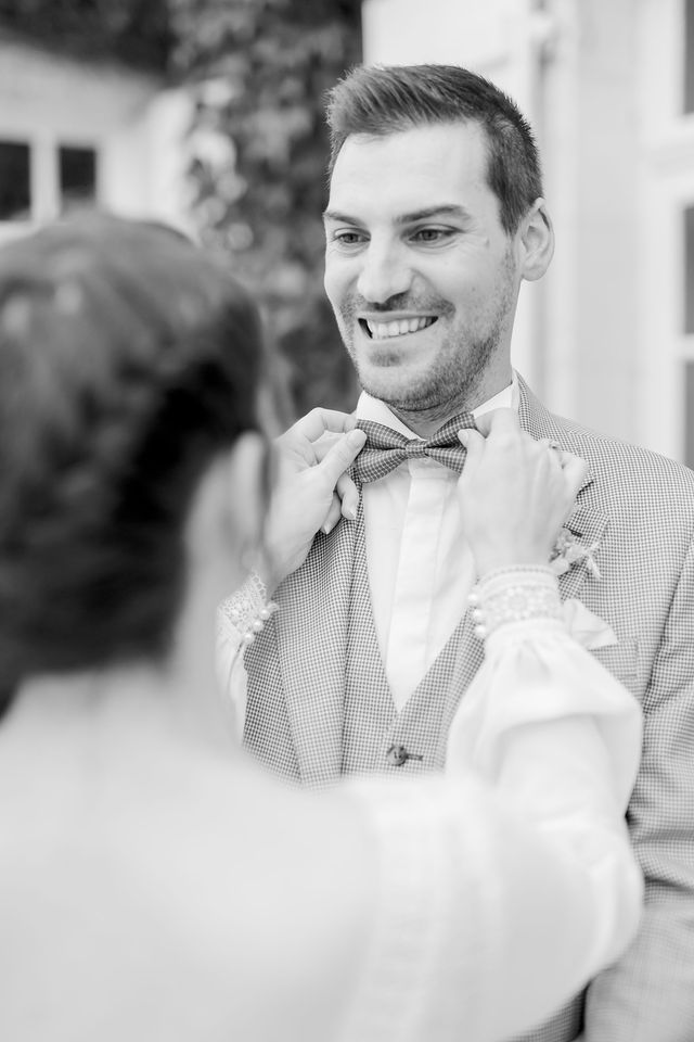 Black and white photograph showing groom wearing checkered suit and bow tie.