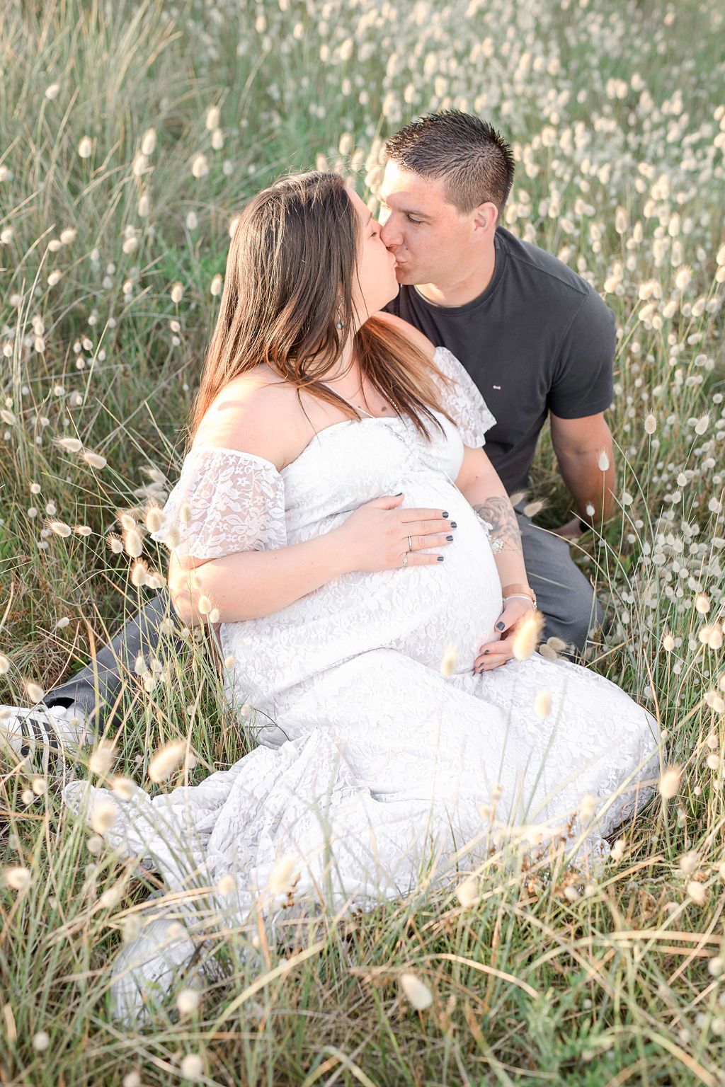 Two people rest together in a field of white flowers during a summer evening.