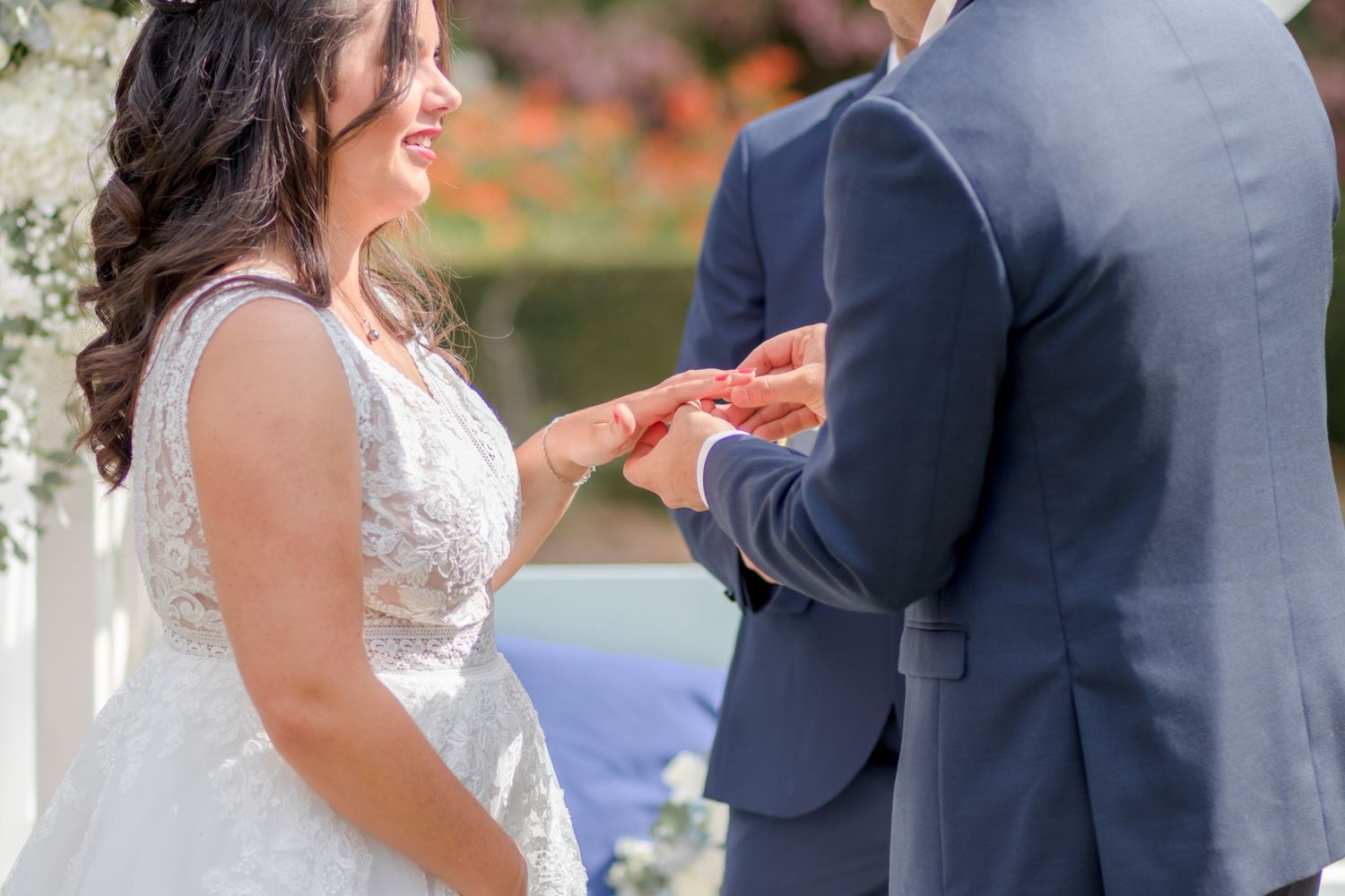Close-up of wedding ring exchange during outdoor garden ceremony.