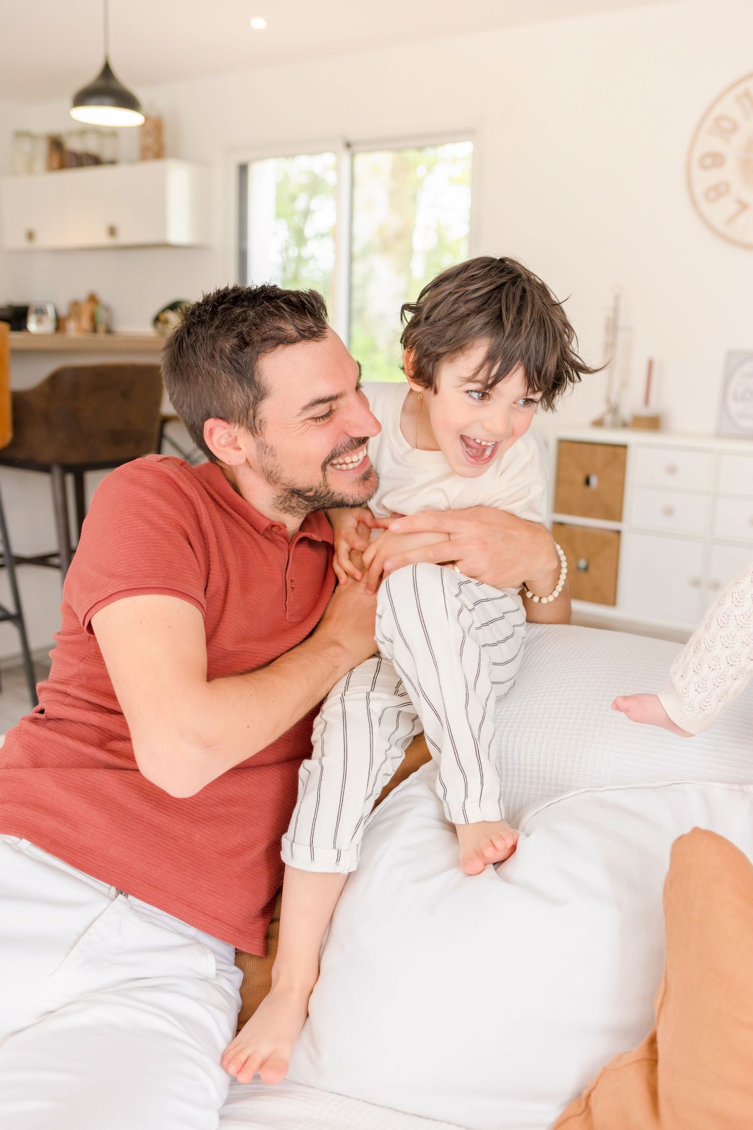 Family members sharing tender moments while relaxing on white furniture in a modern space.