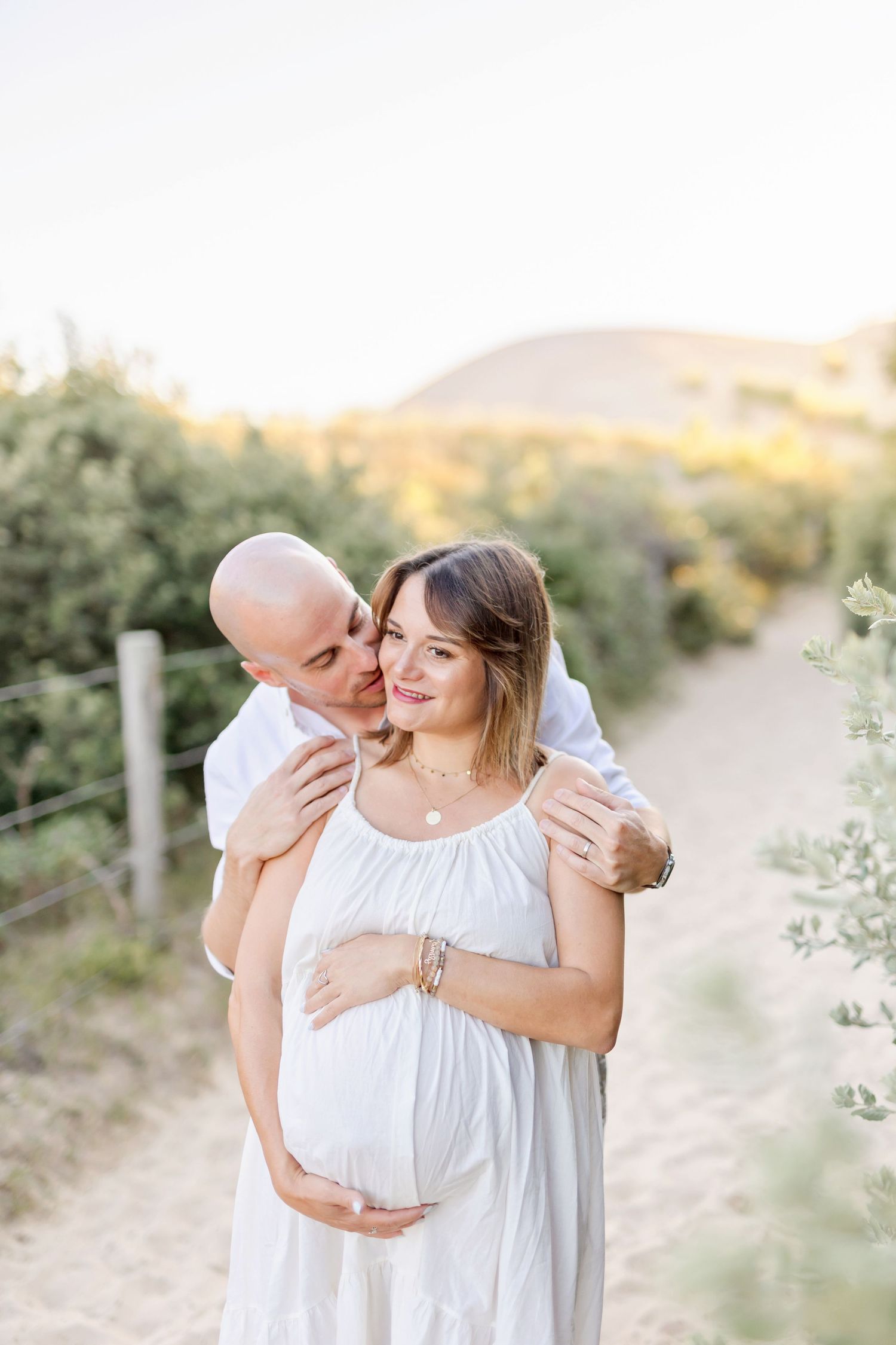 Tender maternity moment captured on a scenic hiking trail during golden hour.