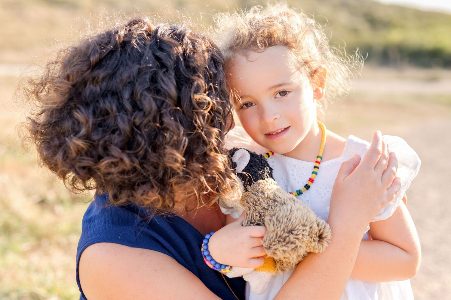 Sweet moment between parent and child sharing smiles in warm sunlight.