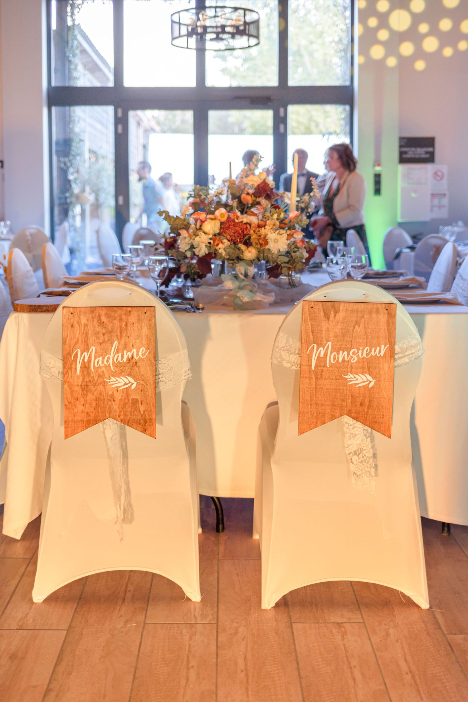 Wedding reception hall with white chair covers and custom signage for seating arrangements.