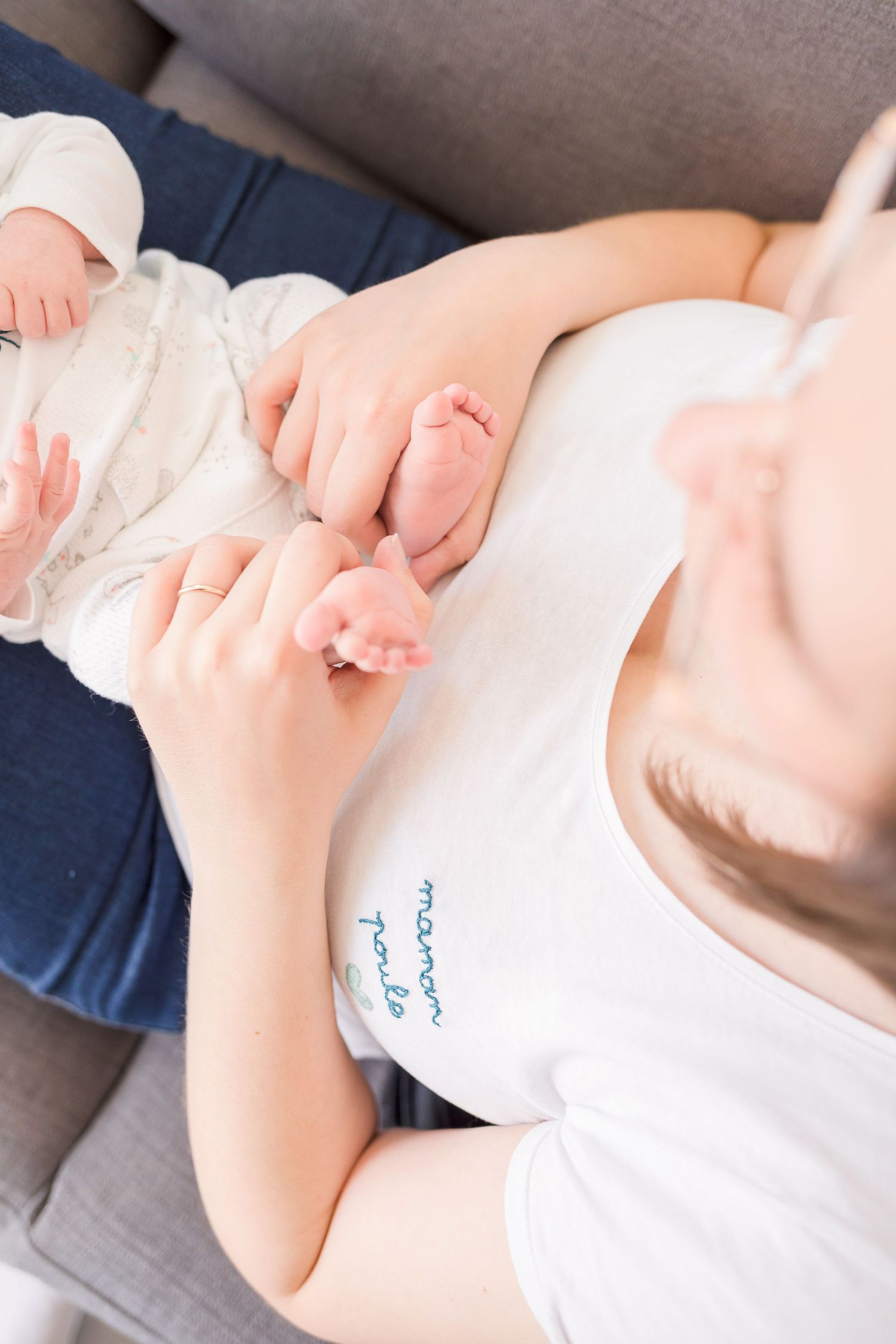 Close up of tiny baby hands and white onesie with text detail.