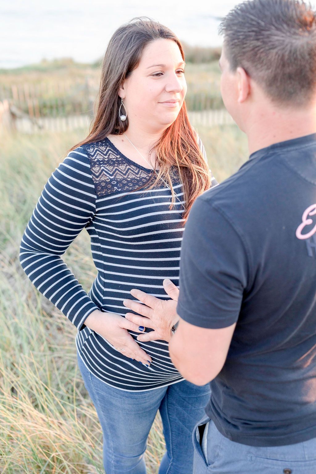 Maternity portrait in striped top against coastal grass background.