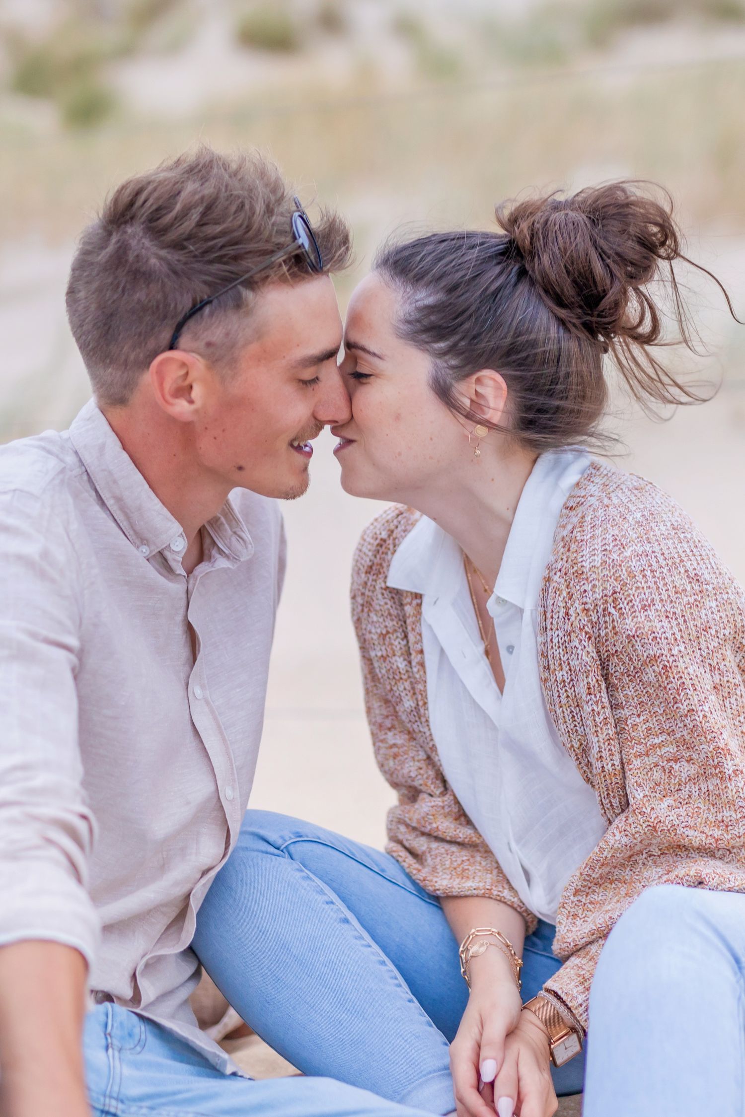 Romantic beach portrait showing tender moment between couple in light colored clothing.