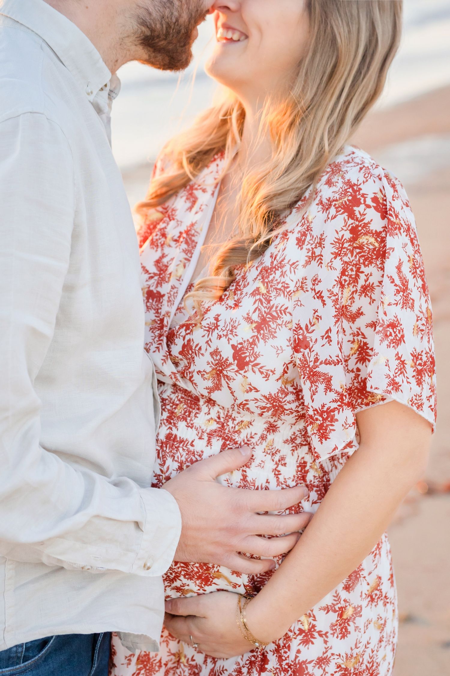 A close-up of a couple embracing, with sunlight illuminating a floral dress and white shirt.