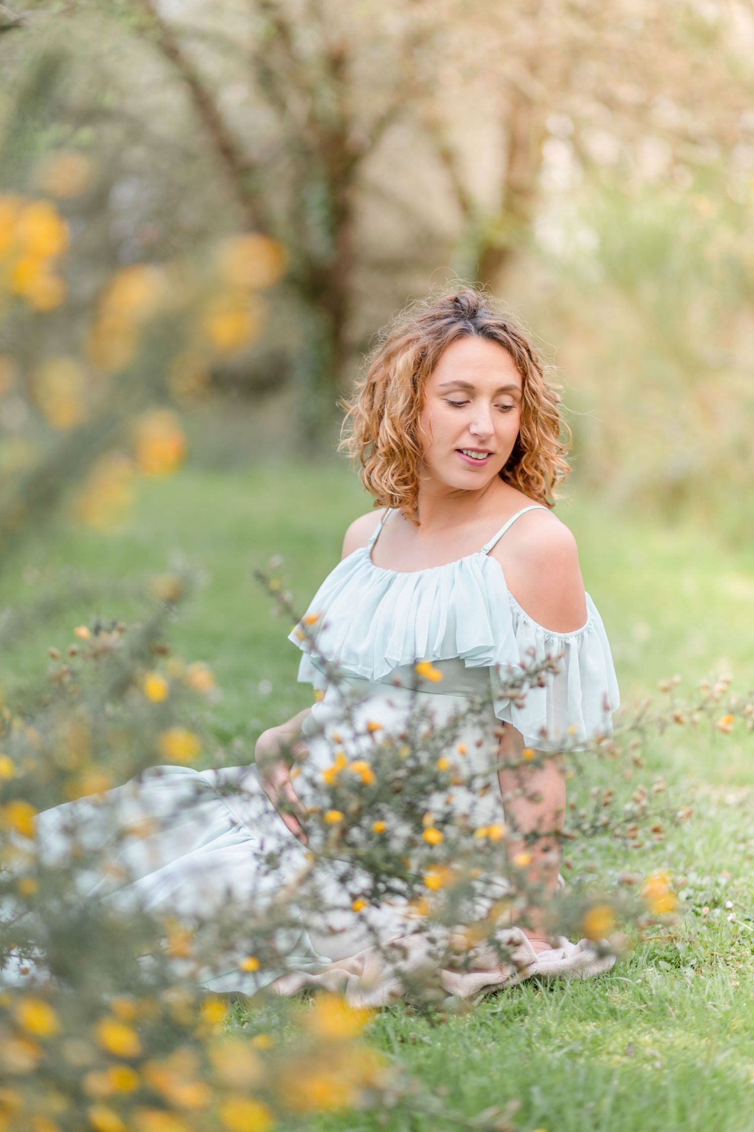 Dreamy spring maternity photos with yellow wildflowers in a sunlit meadow.