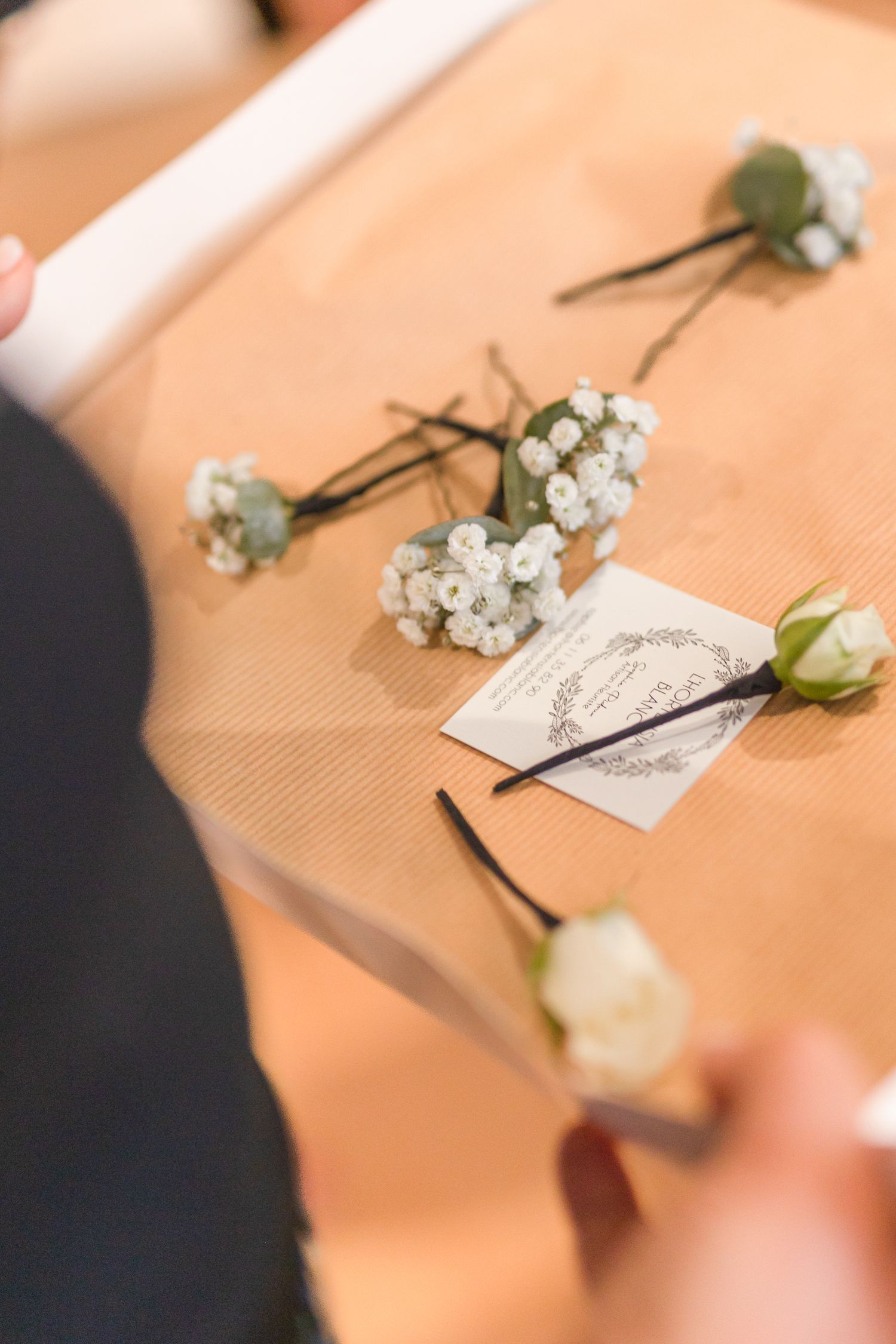 Delicate white flowers and floral pins arranged on a peach-colored surface.