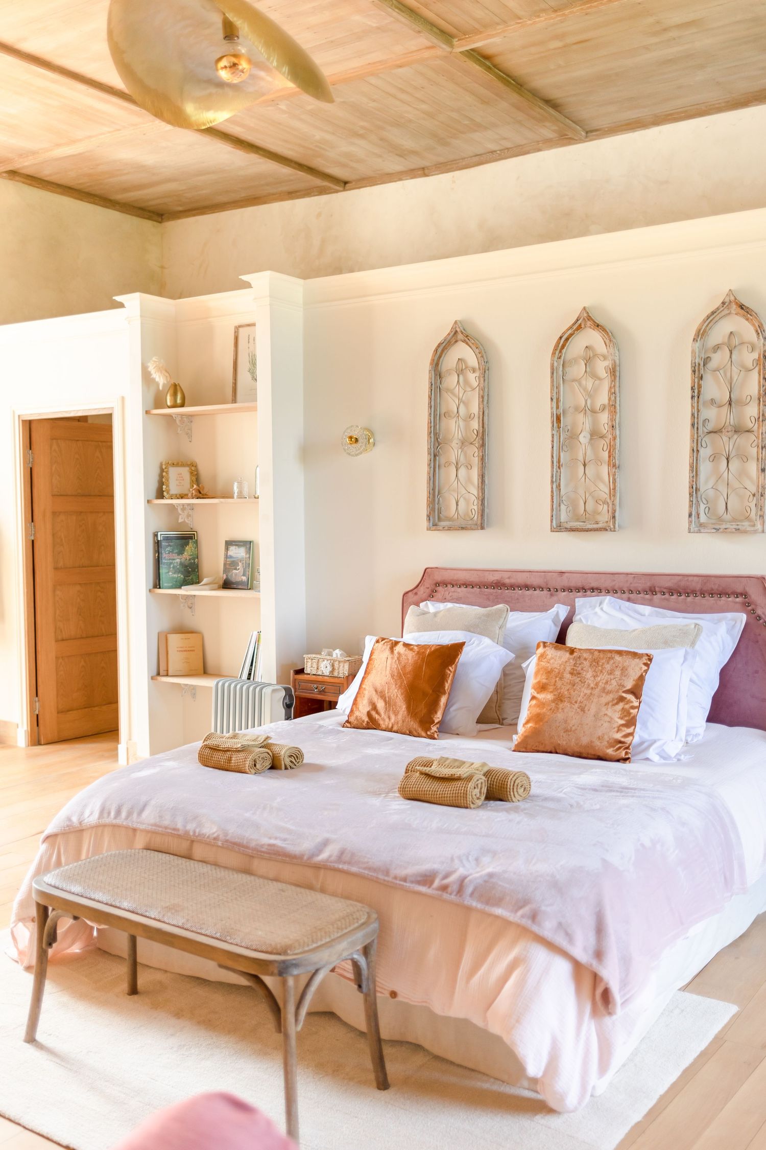 Spacious bedroom with wooden ceiling, white walls, and pink accents.