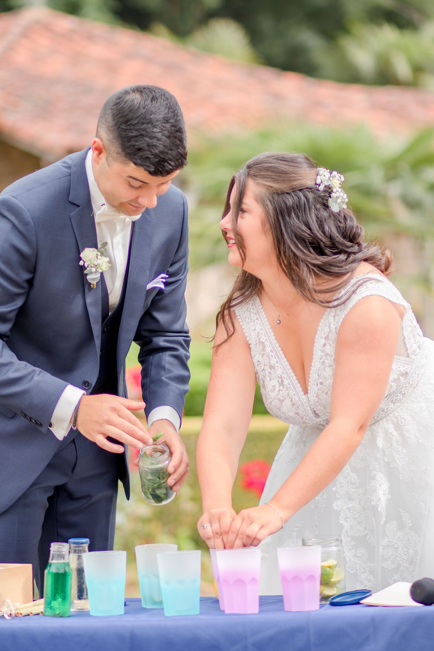 A couple pouring colorful drinks during their wedding celebration outdoor.