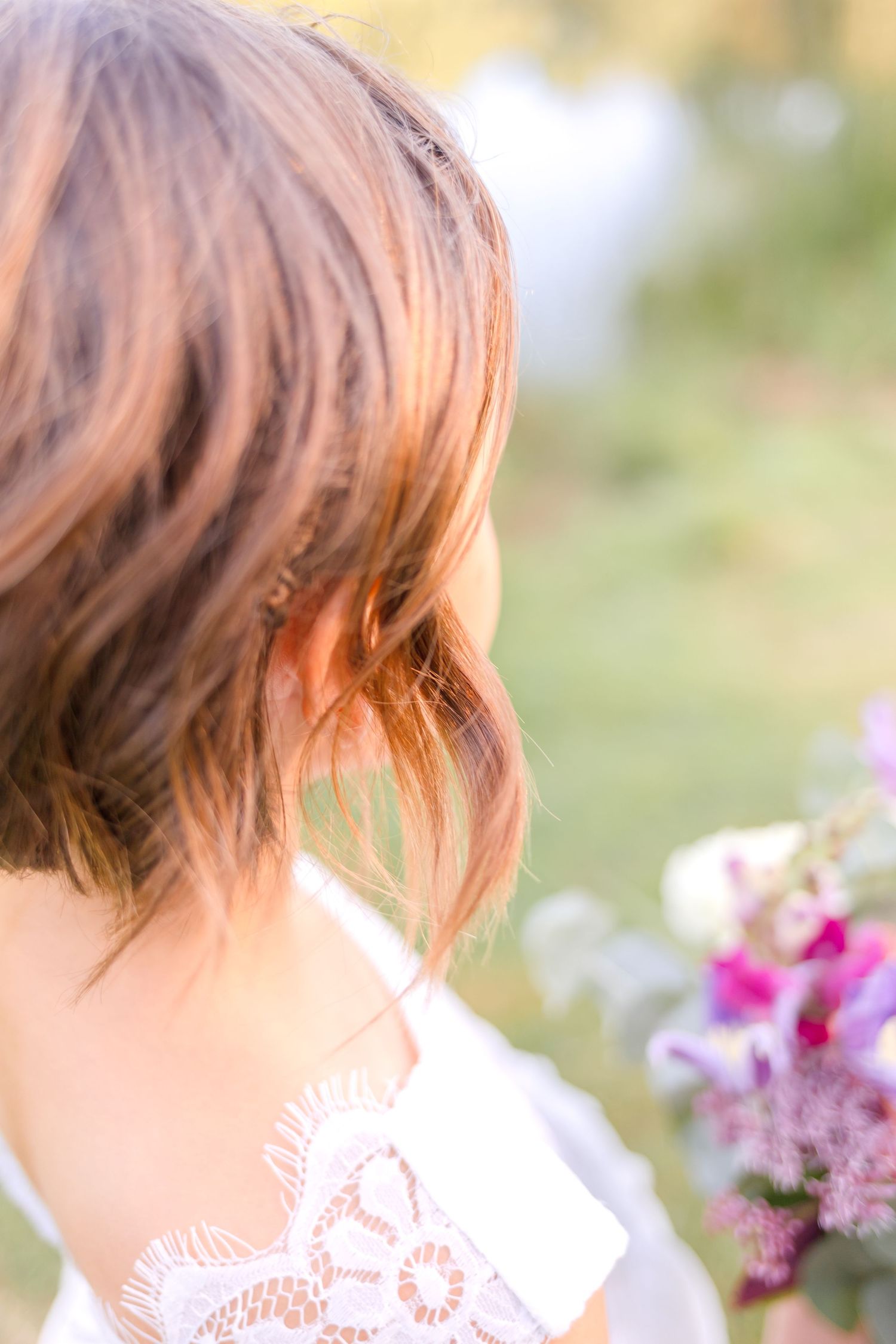 Soft focus detail of bridal hairstyle with pink flowers.