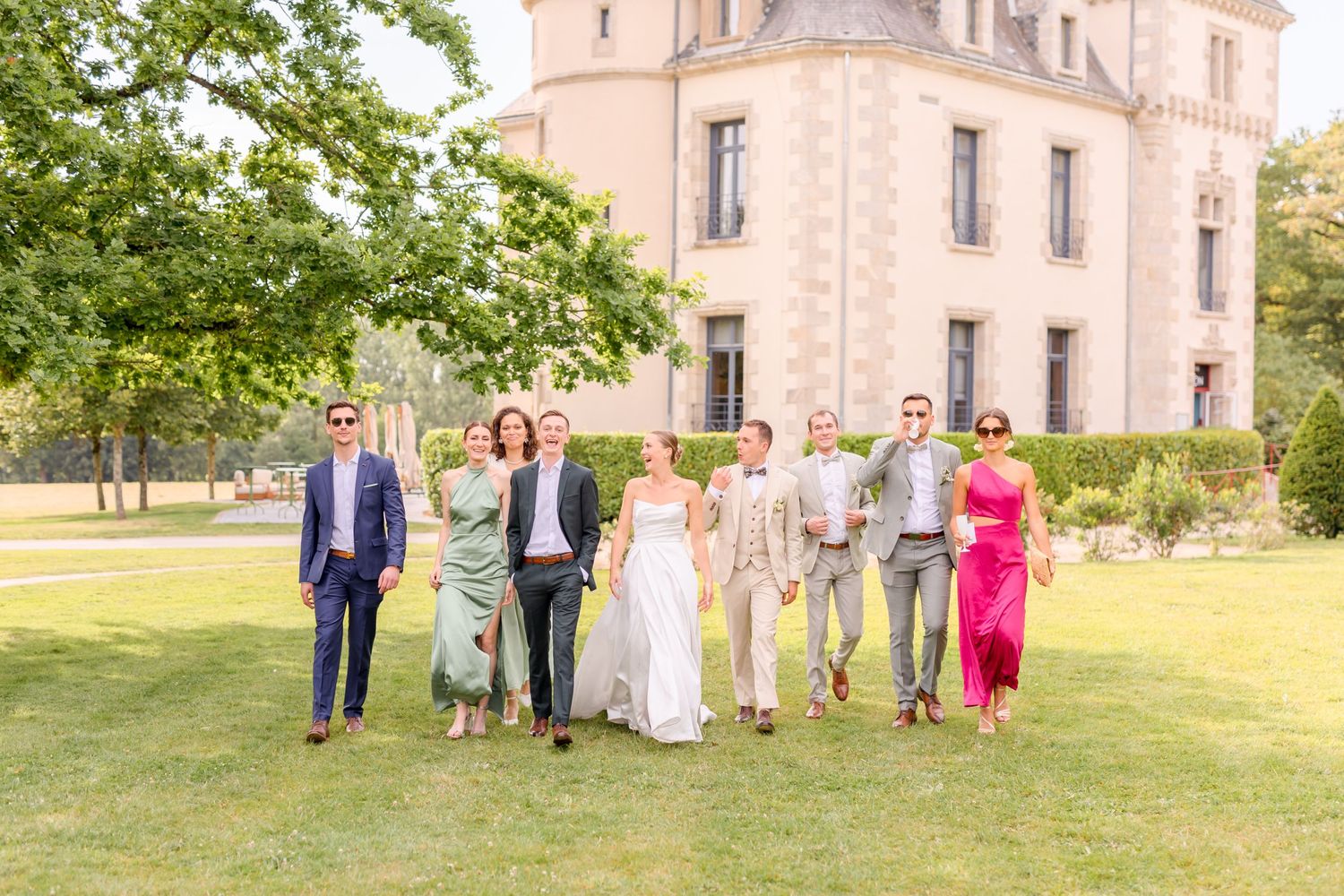 Wedding party arranges for formal group photos on the lawn of a French chateau.