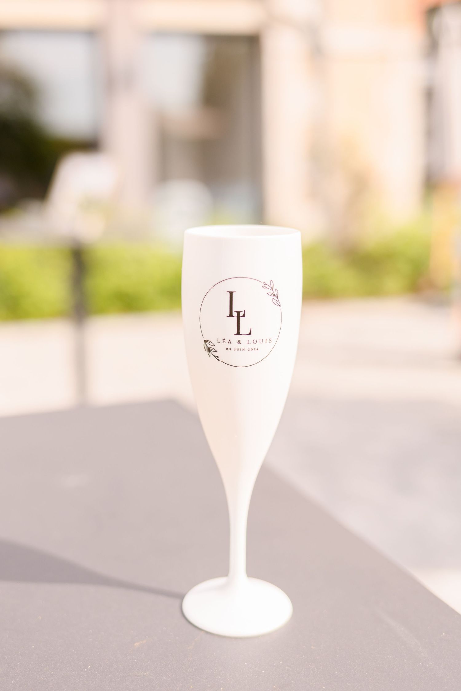 White champagne flute with custom monogram logo on gray surface.