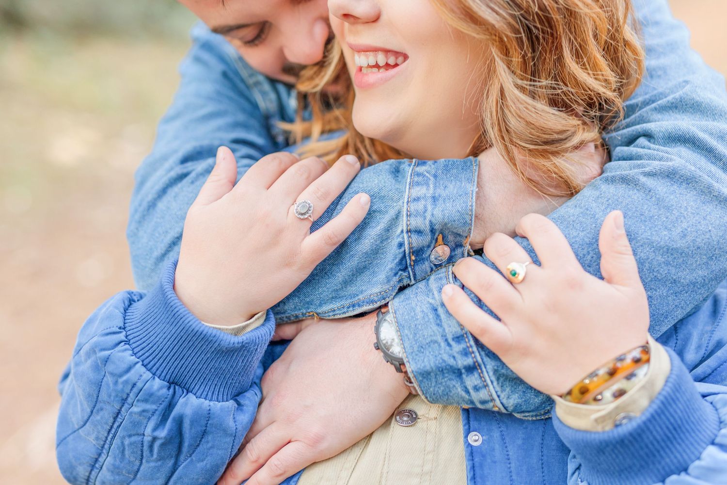 Close-up shot of loving embrace showing engagement ring detail.