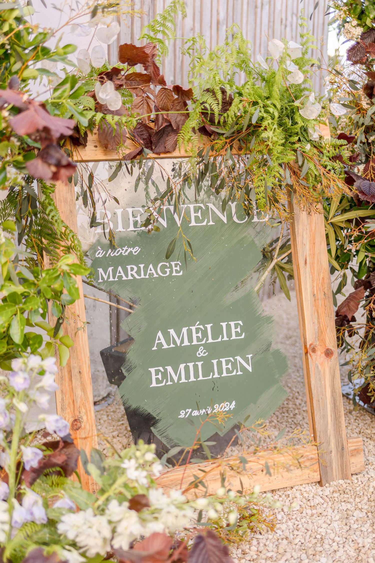 Wedding welcome sign for Amelie and Emilien framed by lush foliage.