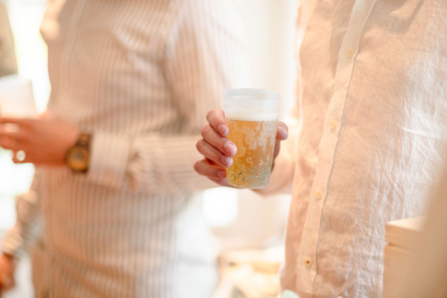 Person holding a clear beverage glass during a social gathering.