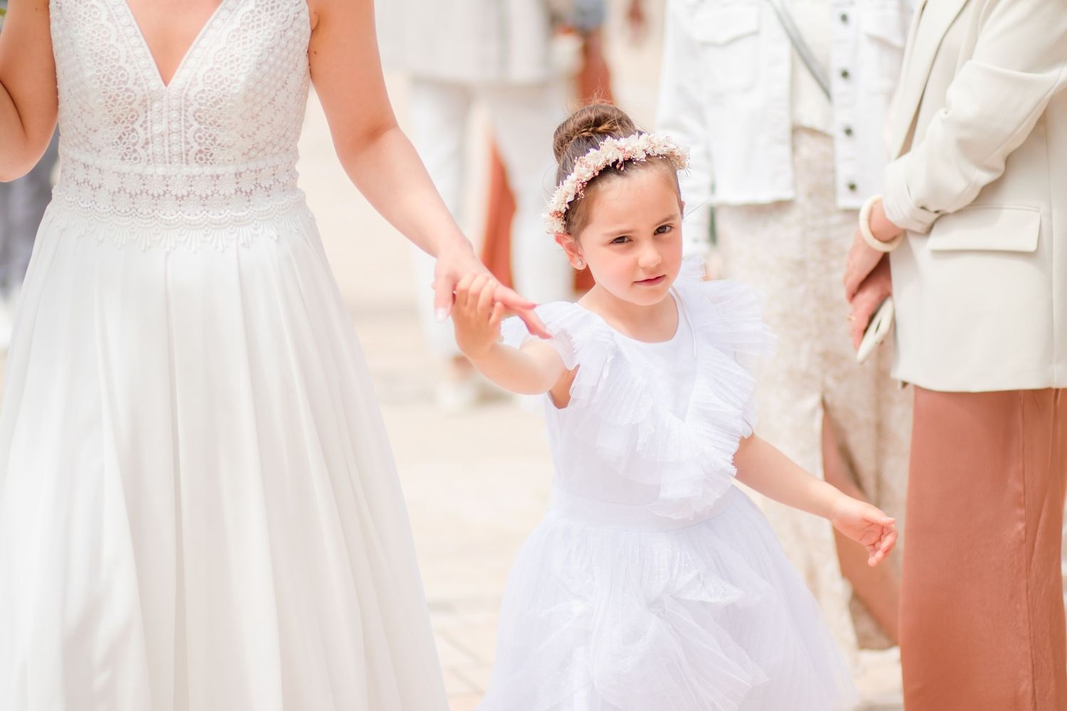 Wedding guests in white dresses gather during outdoor celebration.