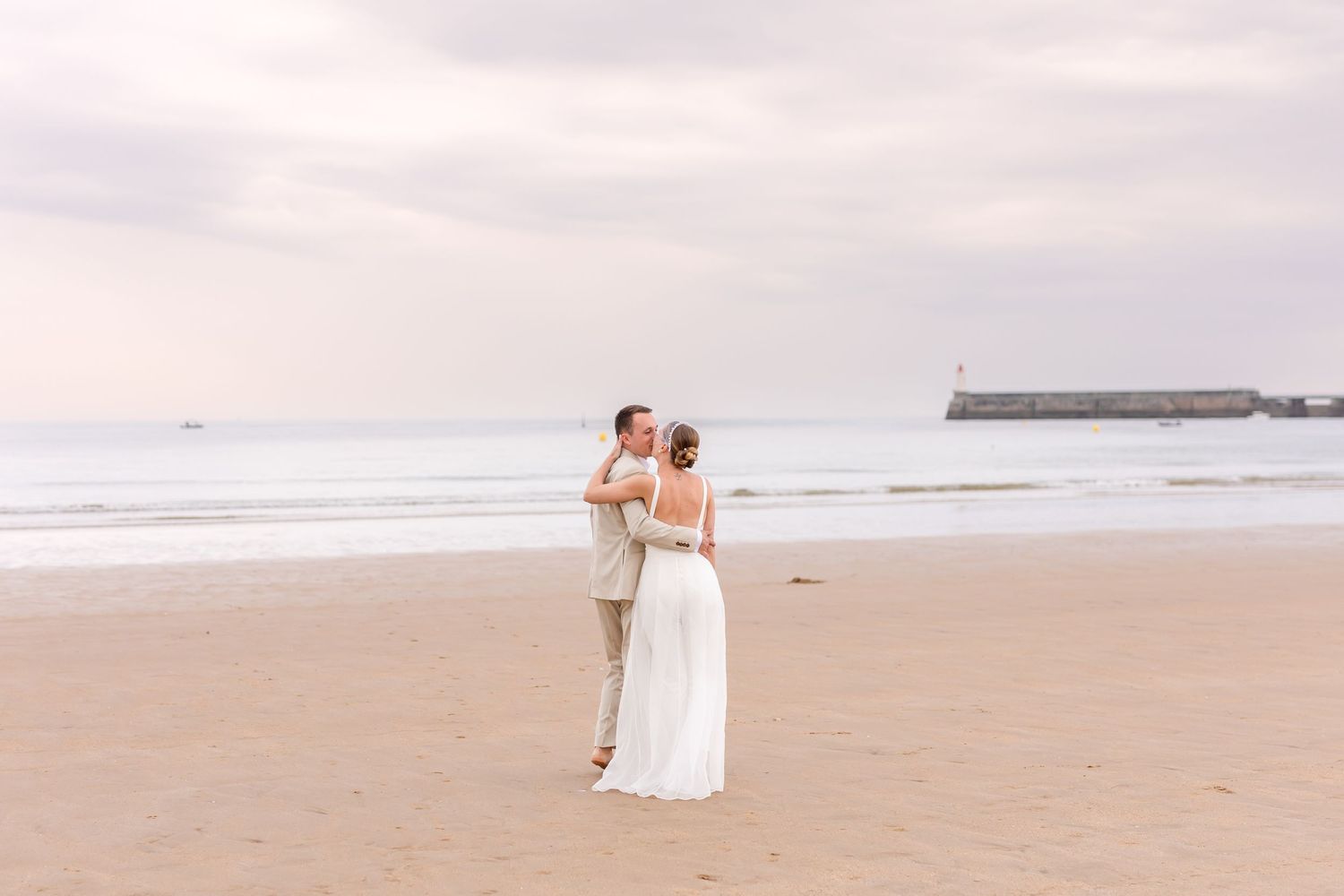 Newlywed couple sharing intimate moment on peaceful beach during sunset.