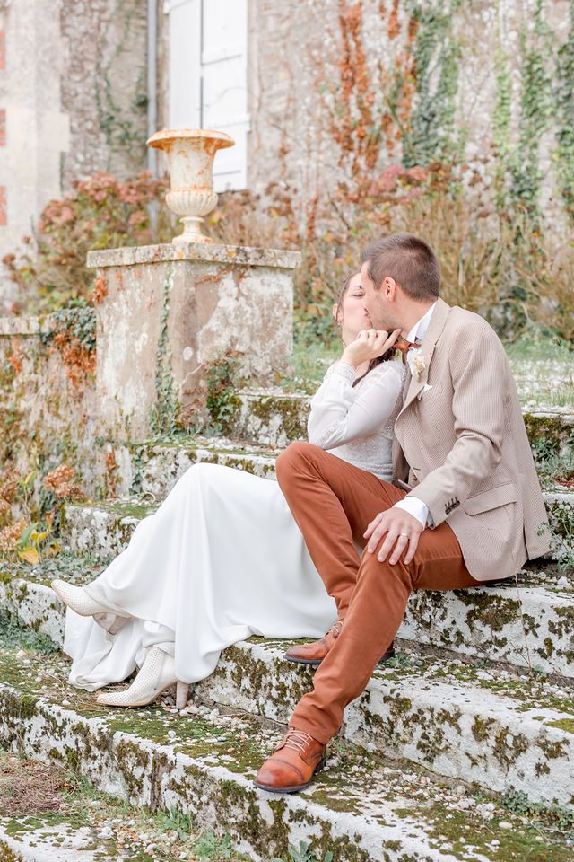 Romantic portrait on weathered stone steps with vintage garden urn and climbing vines.