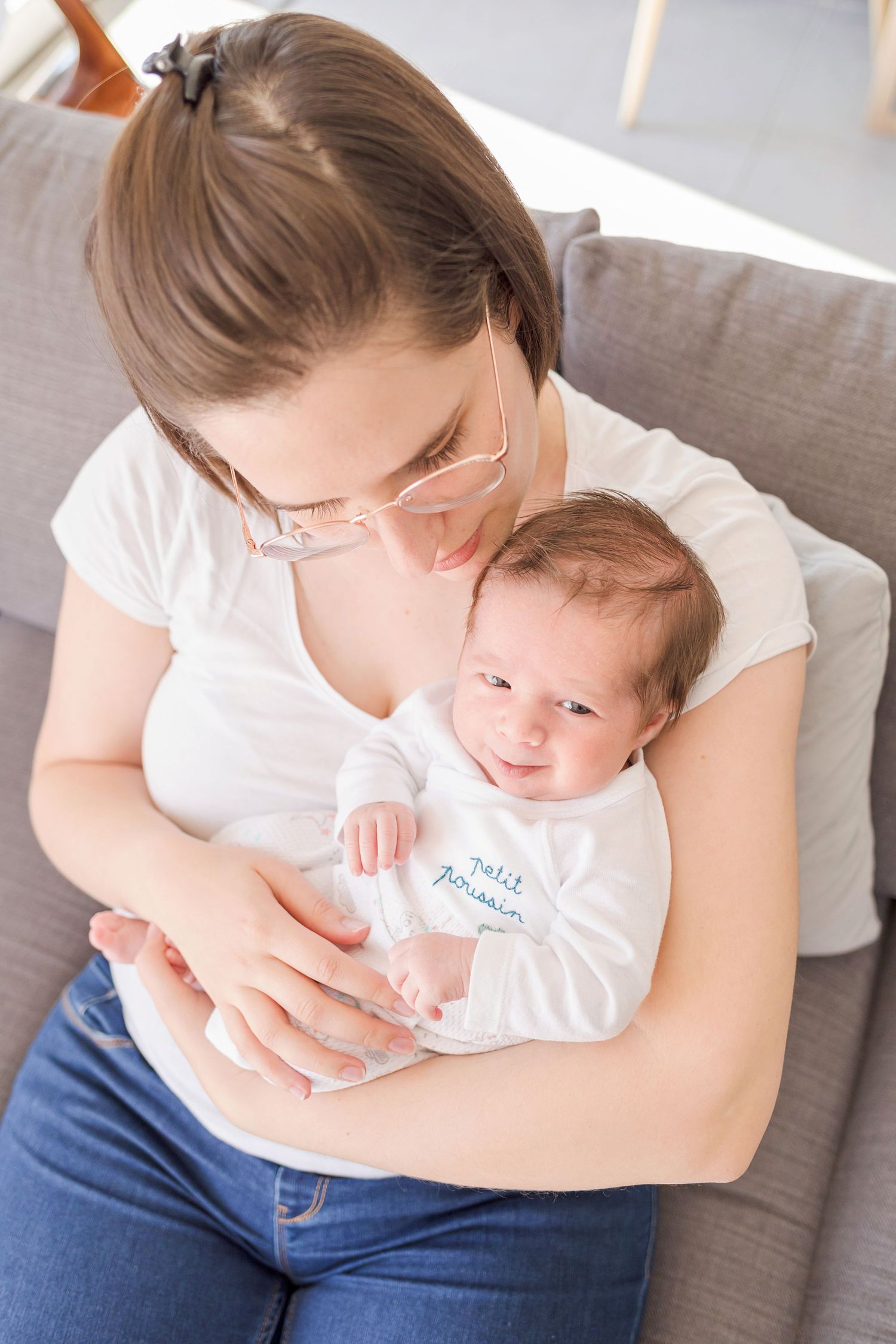 Tender moment shared on a grey couch while holding a small infant.
