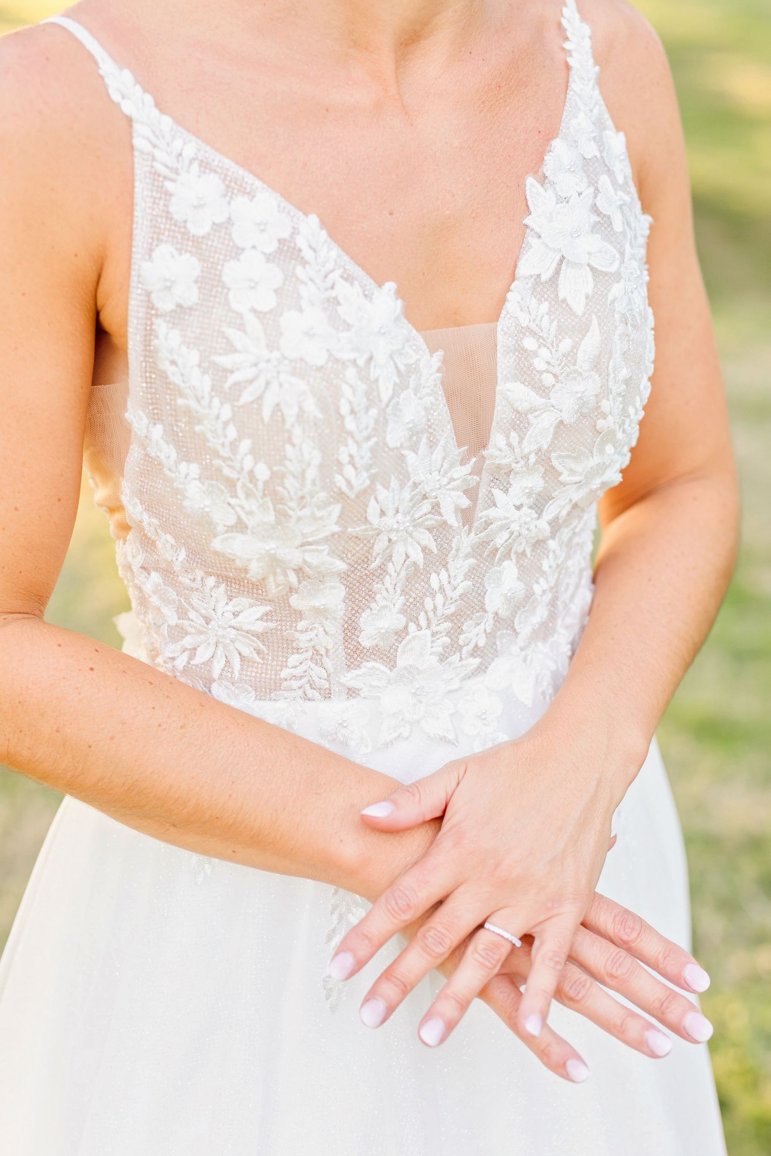 Close-up detail of a white lace wedding dress bodice with intricate floral embroidery.