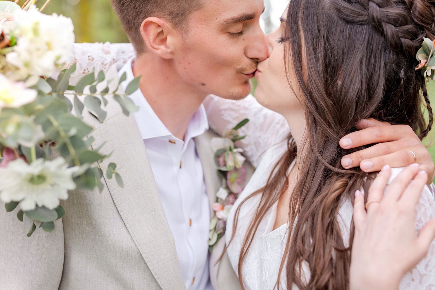 Intimate wedding photography captures tender moments between newlyweds in a forest setting.