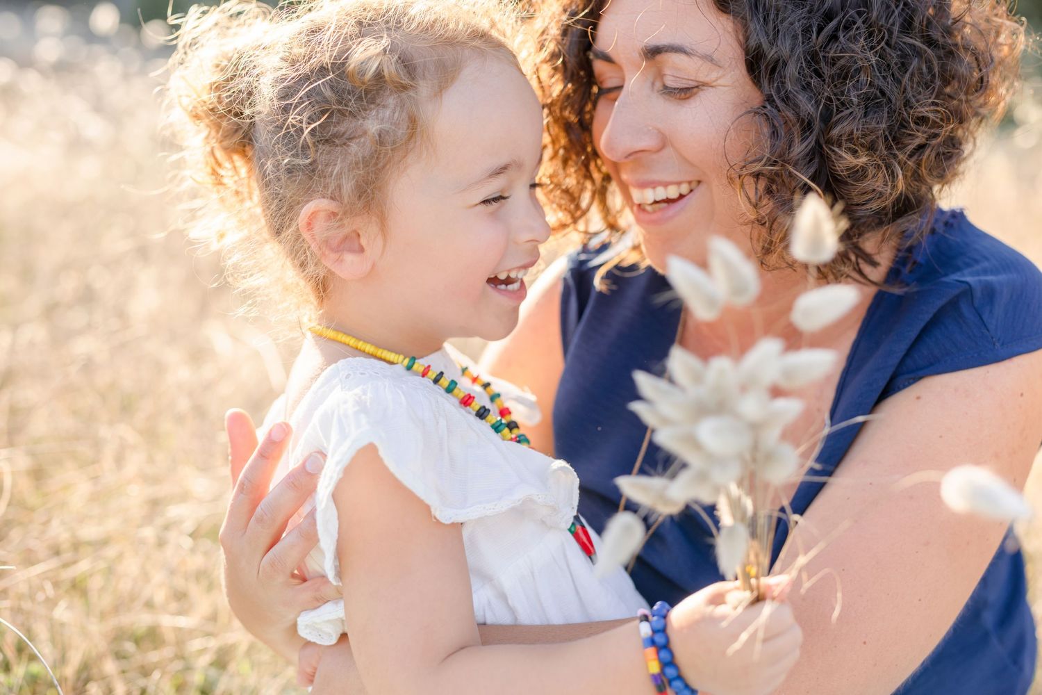 A joyful moment shared in a sunlit field with wildflowers and bokeh lighting effects.