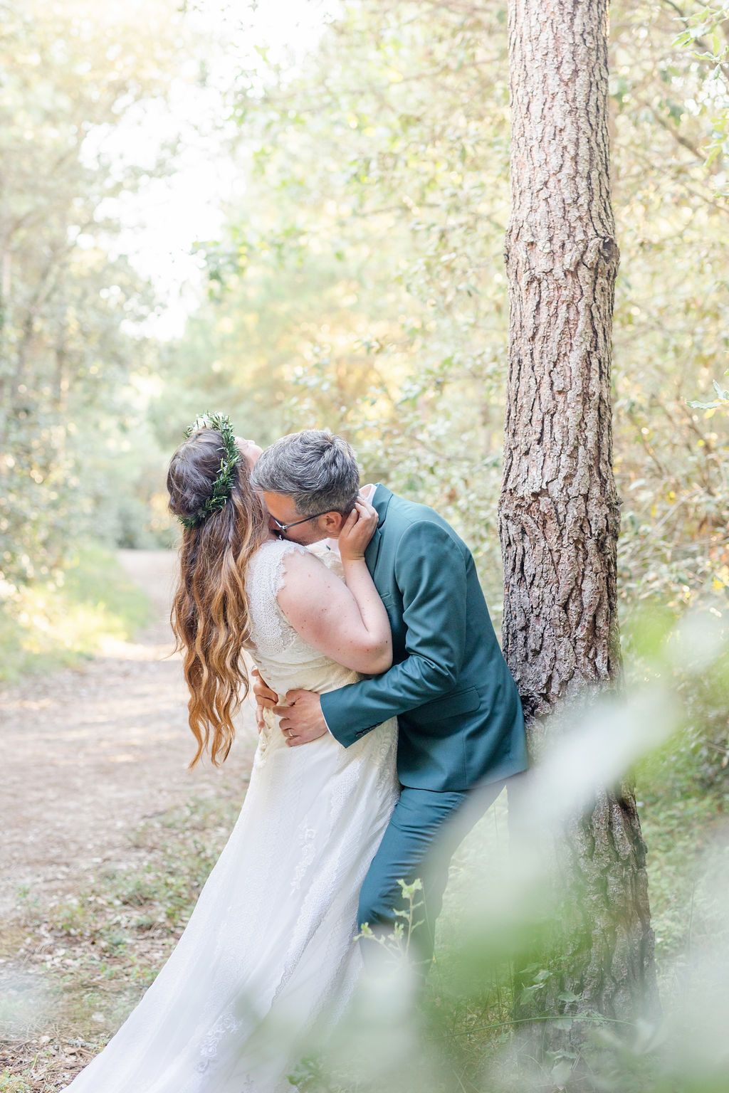 Intimate woodland wedding moment captured with couple sharing a romantic embrace by a pine tree.