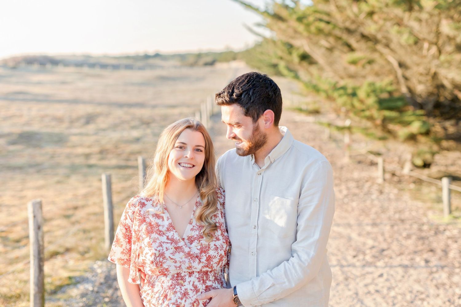 Maternity photo of couple laughing together outdoors with natural lighting.