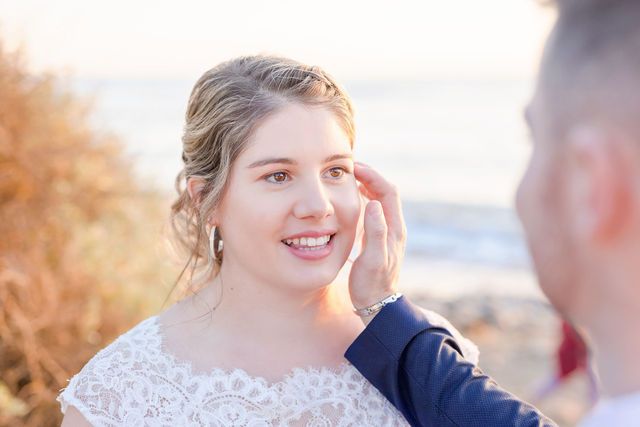 Romantic sunset moment between newlyweds on beach during wedding photoshoot.