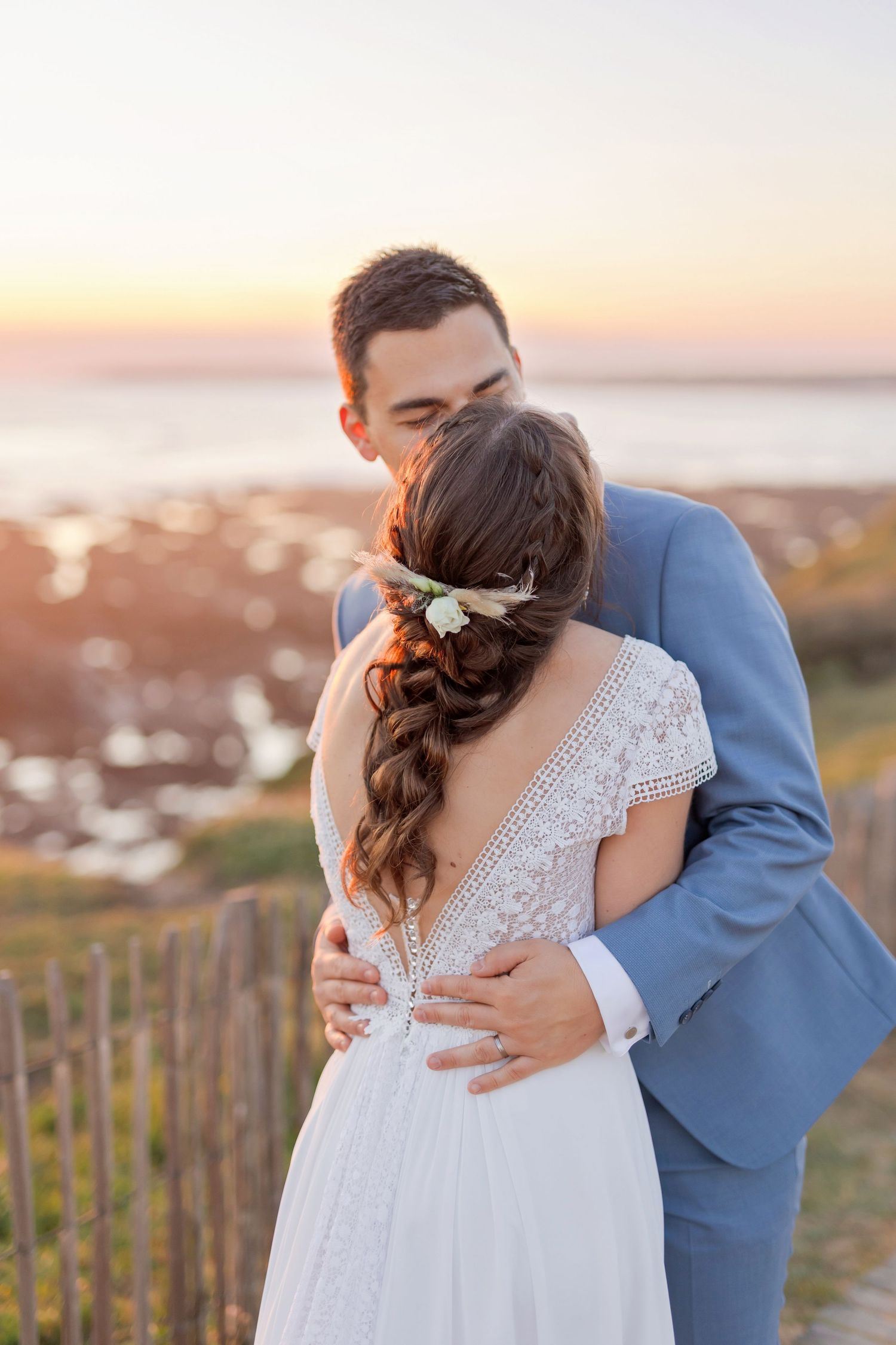 Intimate wedding moment captured on coastal boardwalk during golden hour.