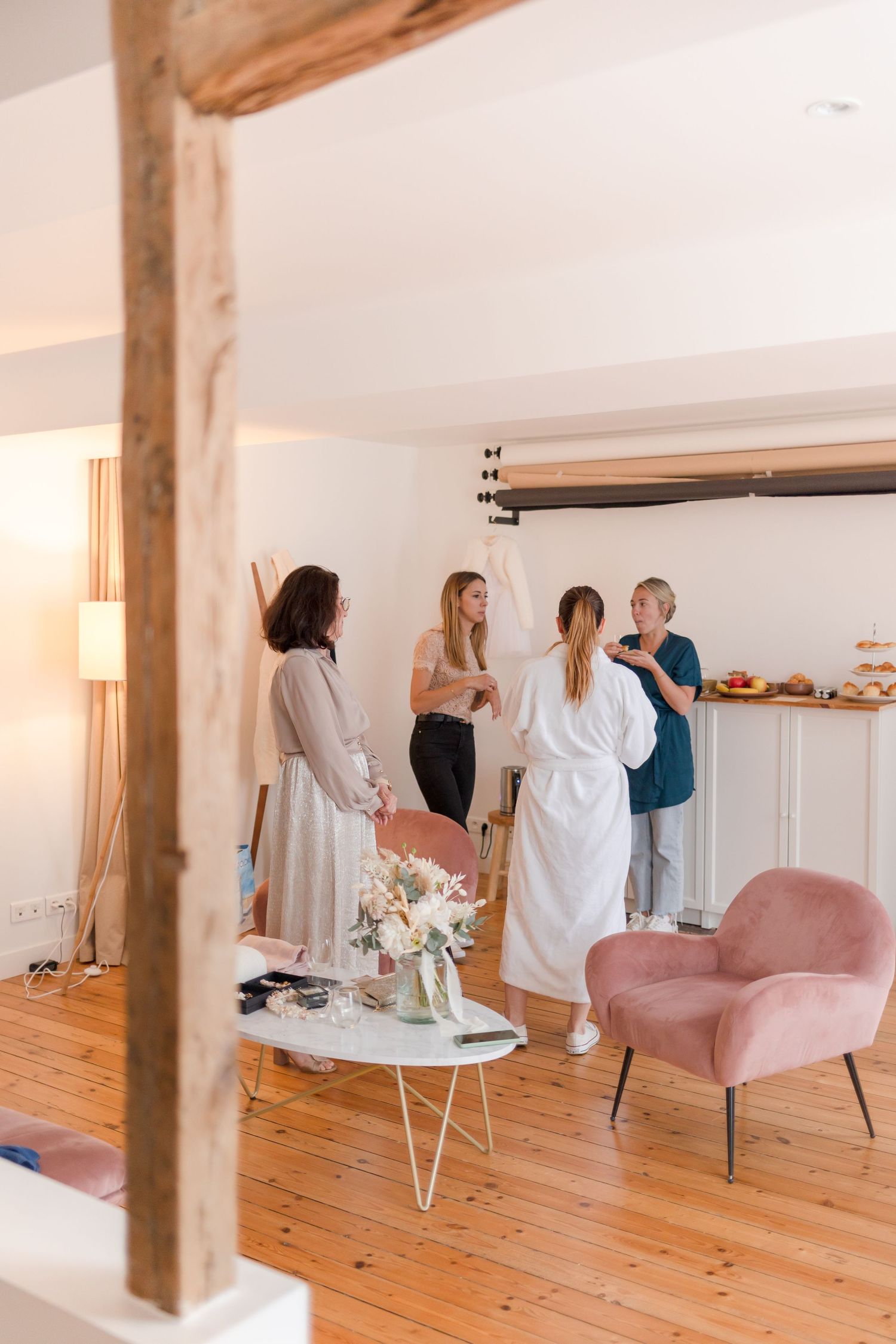 Bright modern interior with exposed wooden beams and pink accent chair.
