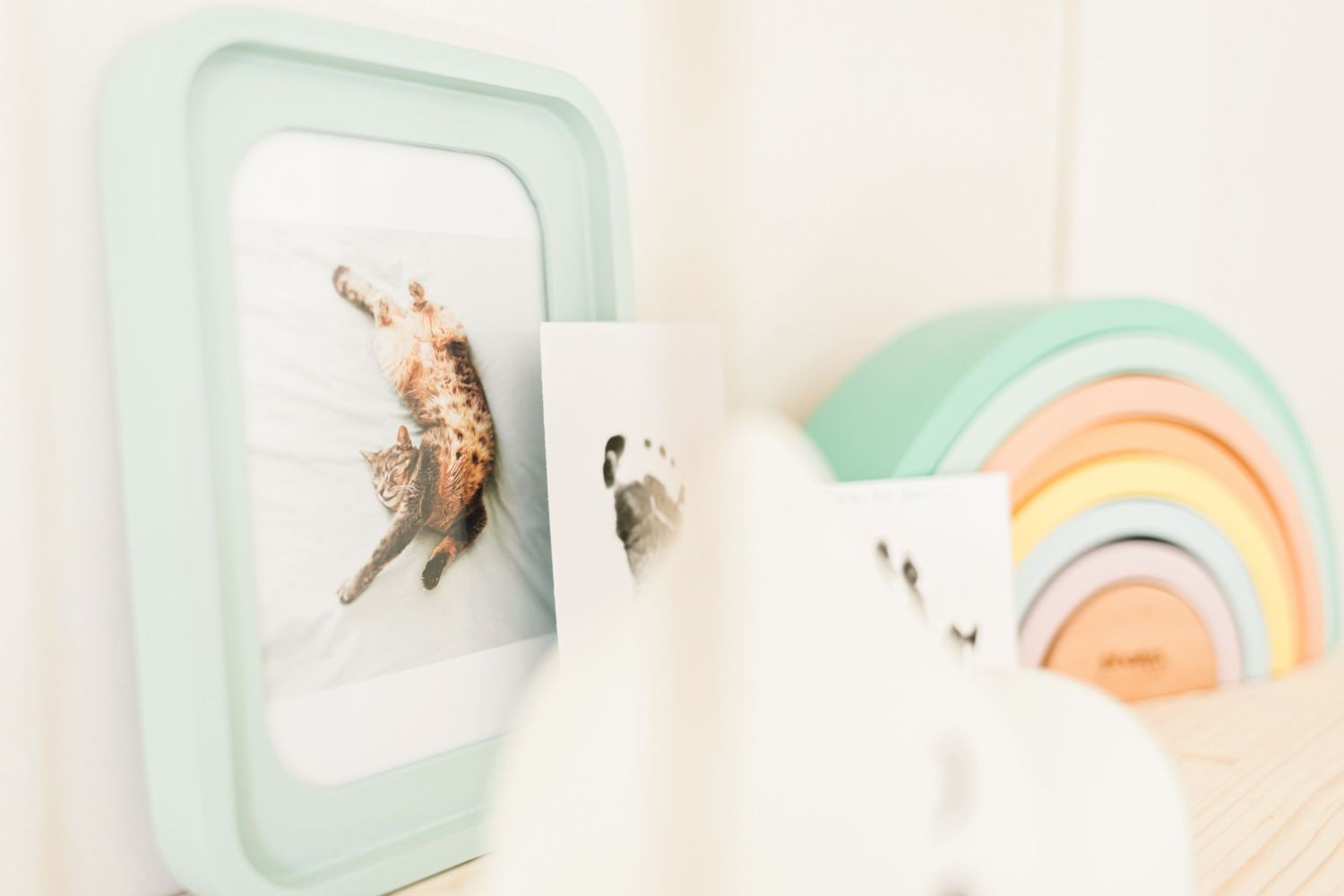 Nursery wall decorated with a mint green frame and rainbow decor in soft pastel colors.