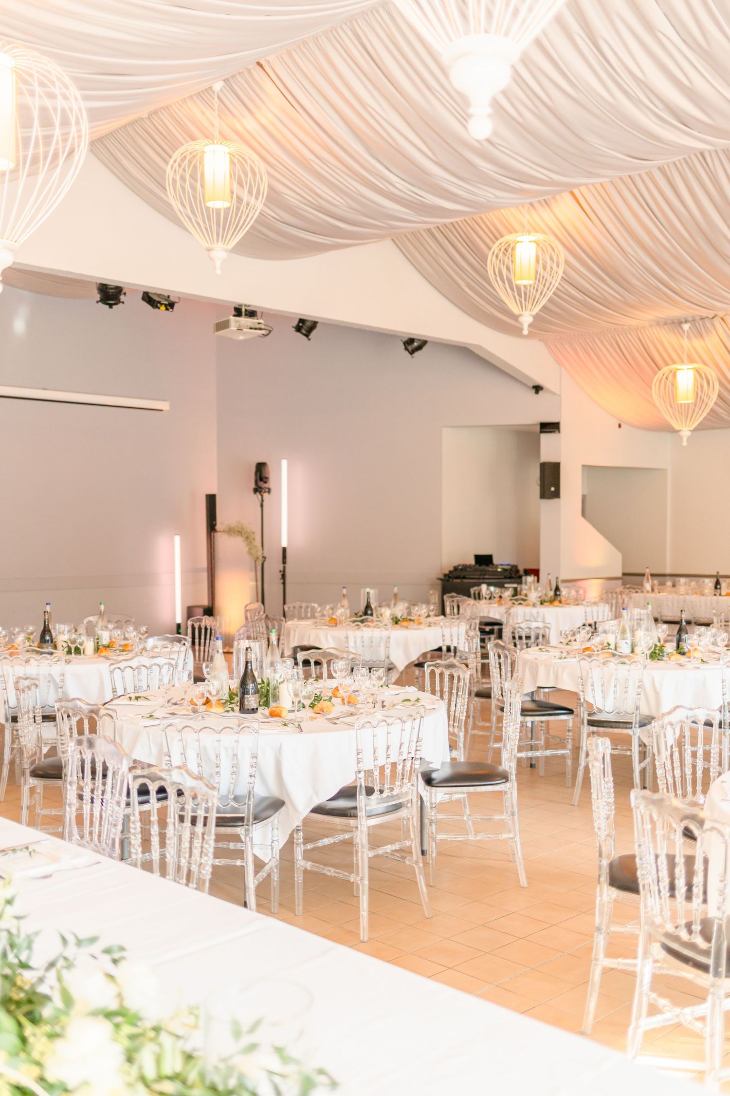Reception hall decorated with flowing white fabric ceiling and warm pendant lighting.