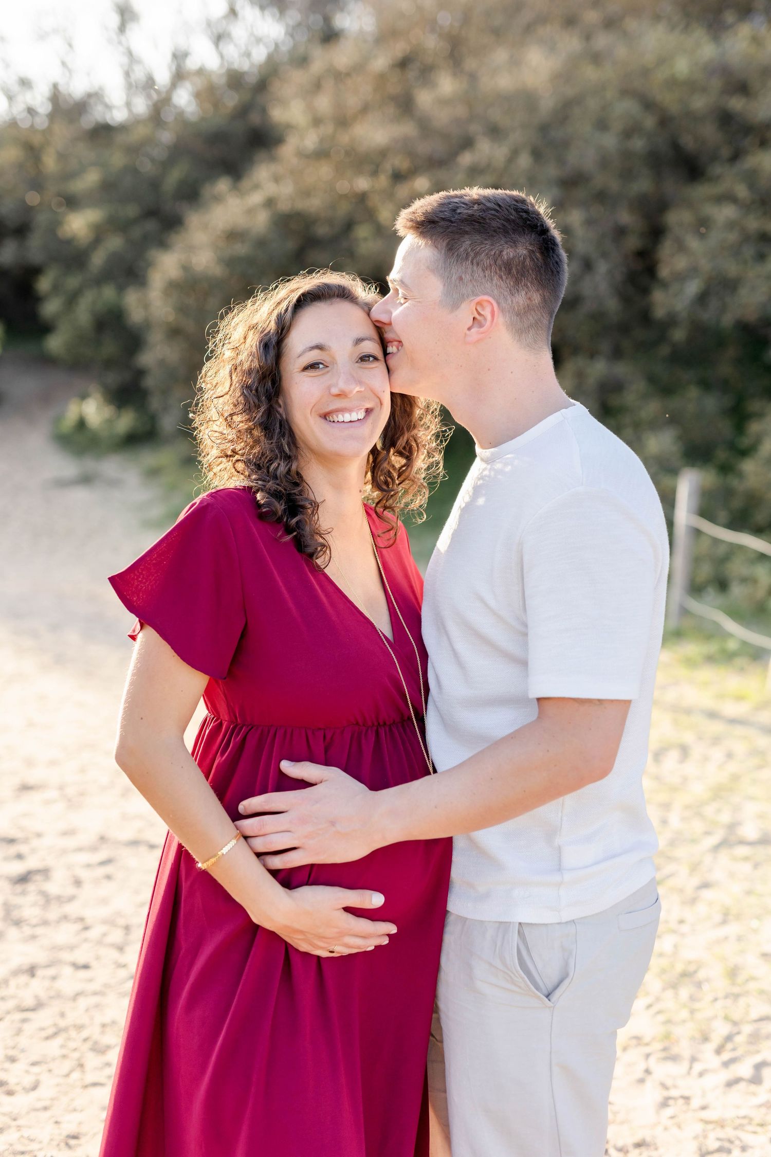 Loving couple shares tender moments during sunset maternity photoshoot in desert setting.