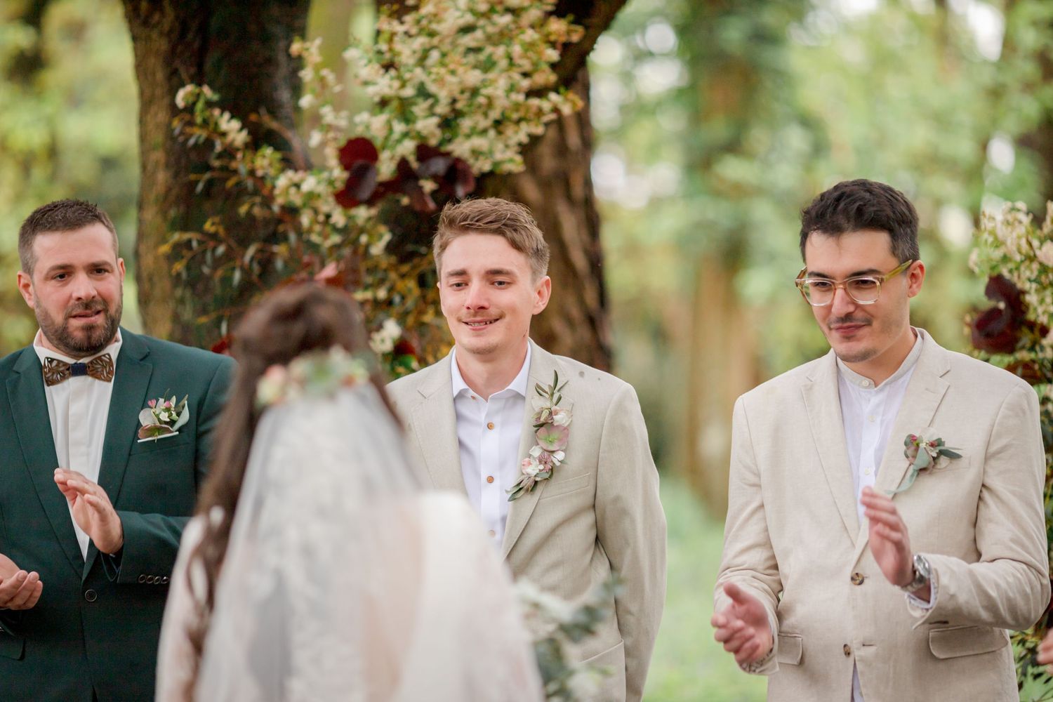 Joyful wedding party members react during outdoor forest ceremony.