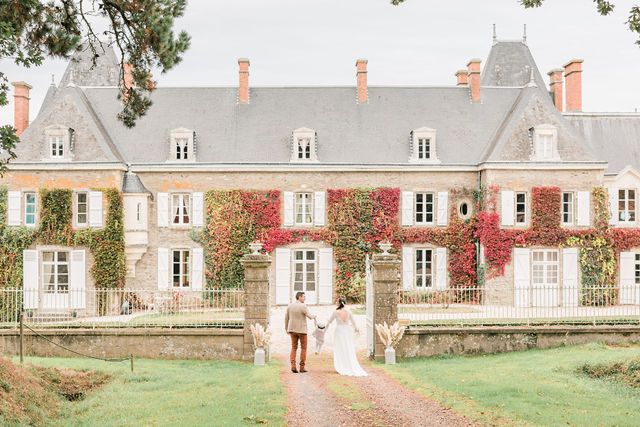 Stately stone mansion with traditional architecture and red climbing vines.