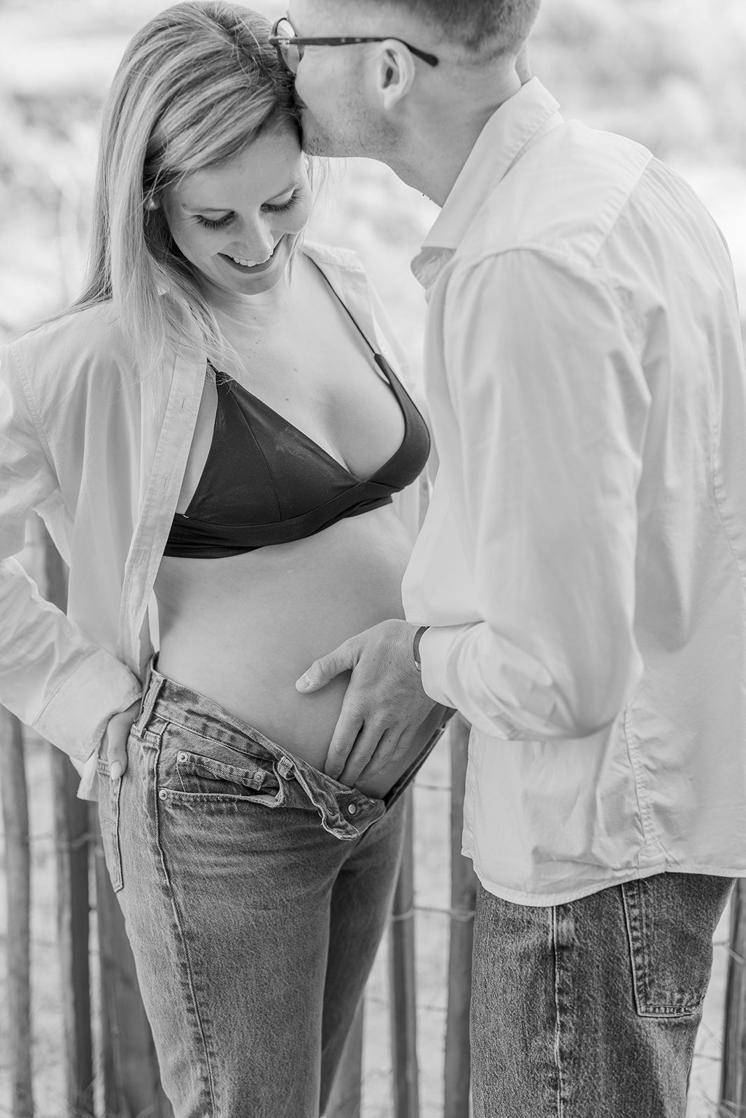 Black and white intimate portrait of a couple embracing, featuring casual denim and a white button-down shirt.