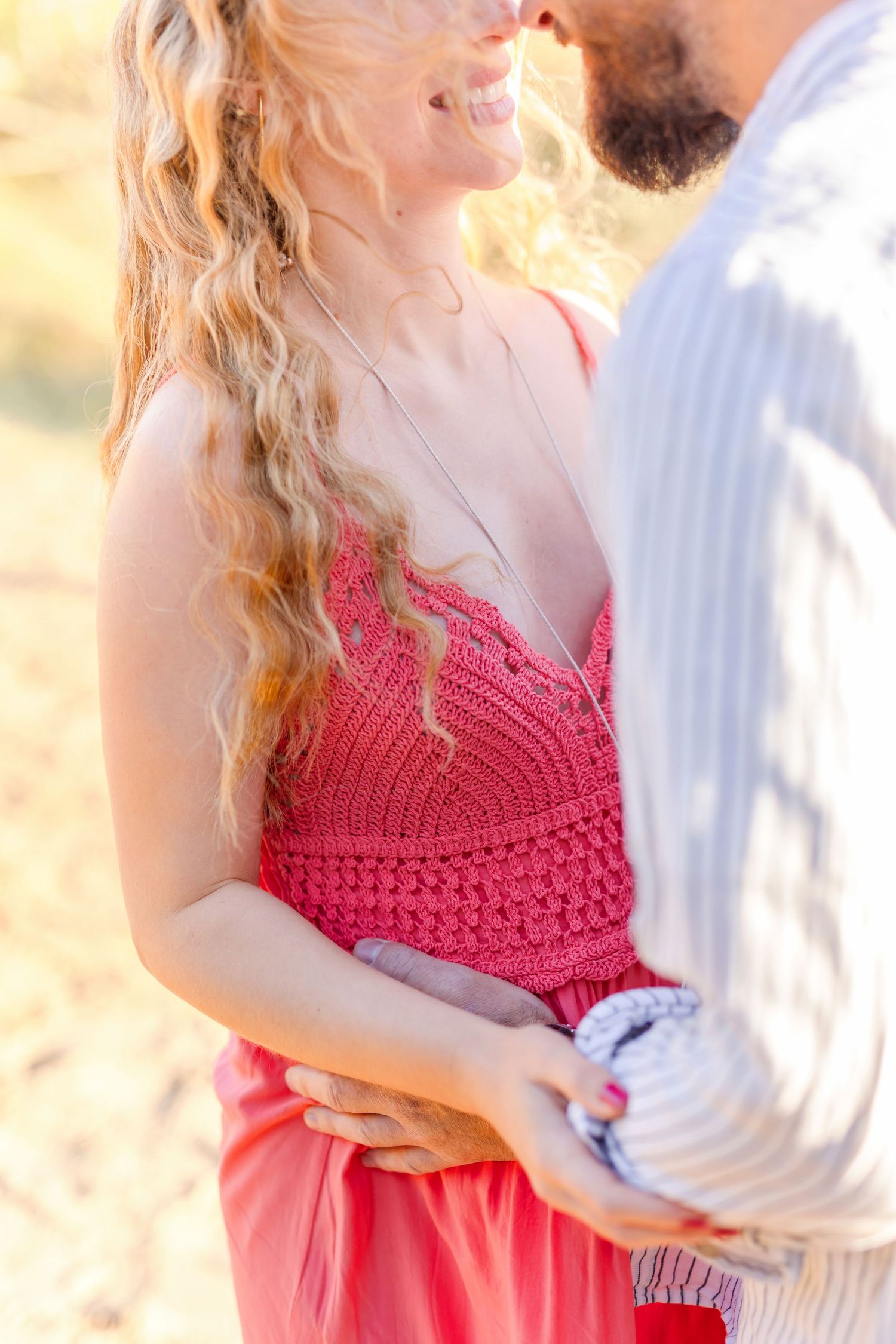 Sunlit detail shot of coral crochet dress during intimate outdoor portrait session.