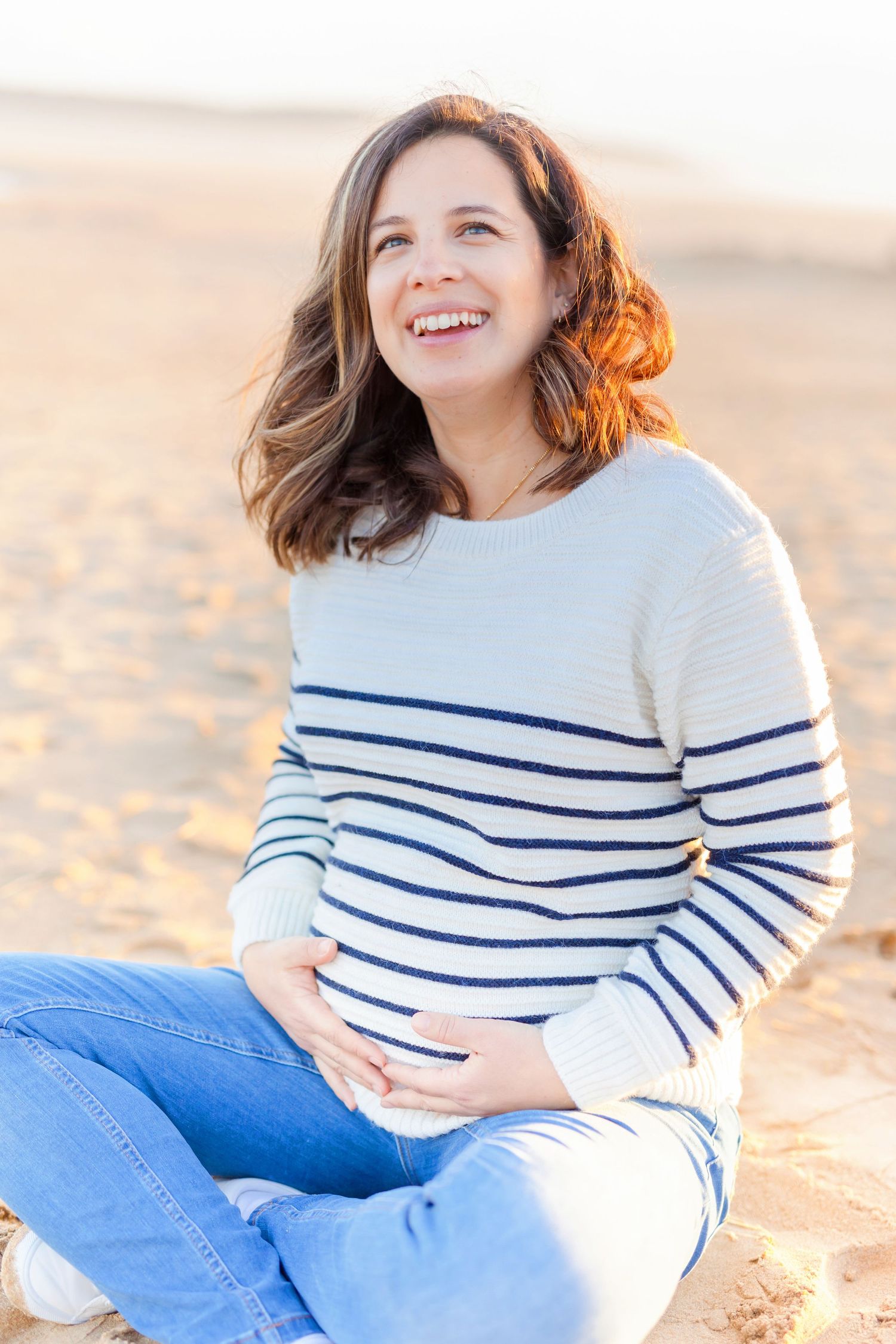 Casual beach portrait featuring someone in a nautical striped sweater and blue jeans.