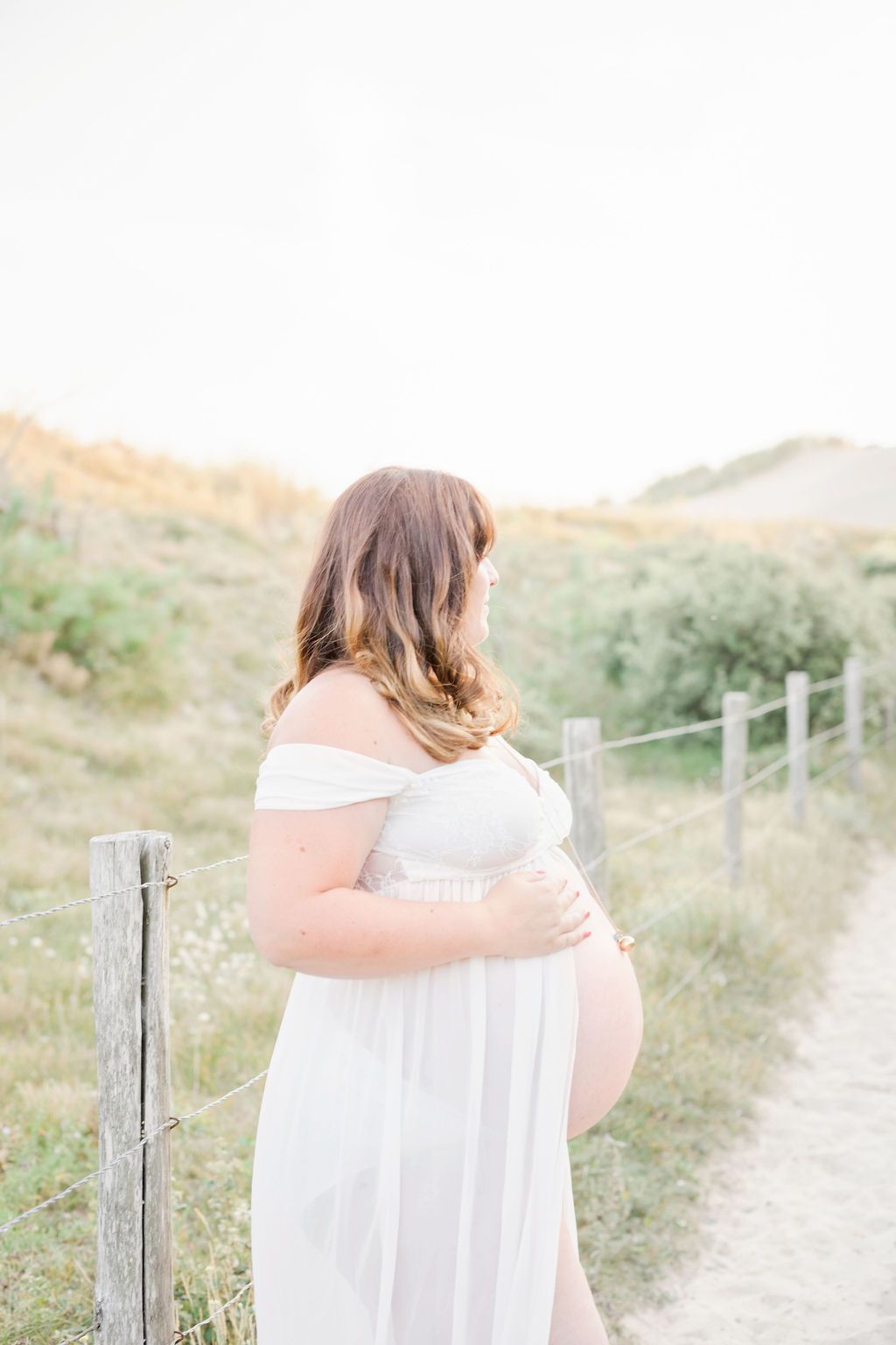 Soft, dreamy beach portrait session on sandy path with weathered fence posts.