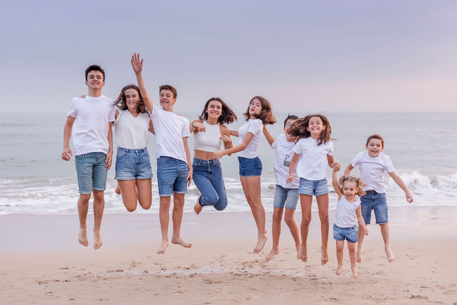 Group of friends jumping together on the beach during a dreamy sunset photoshoot.
