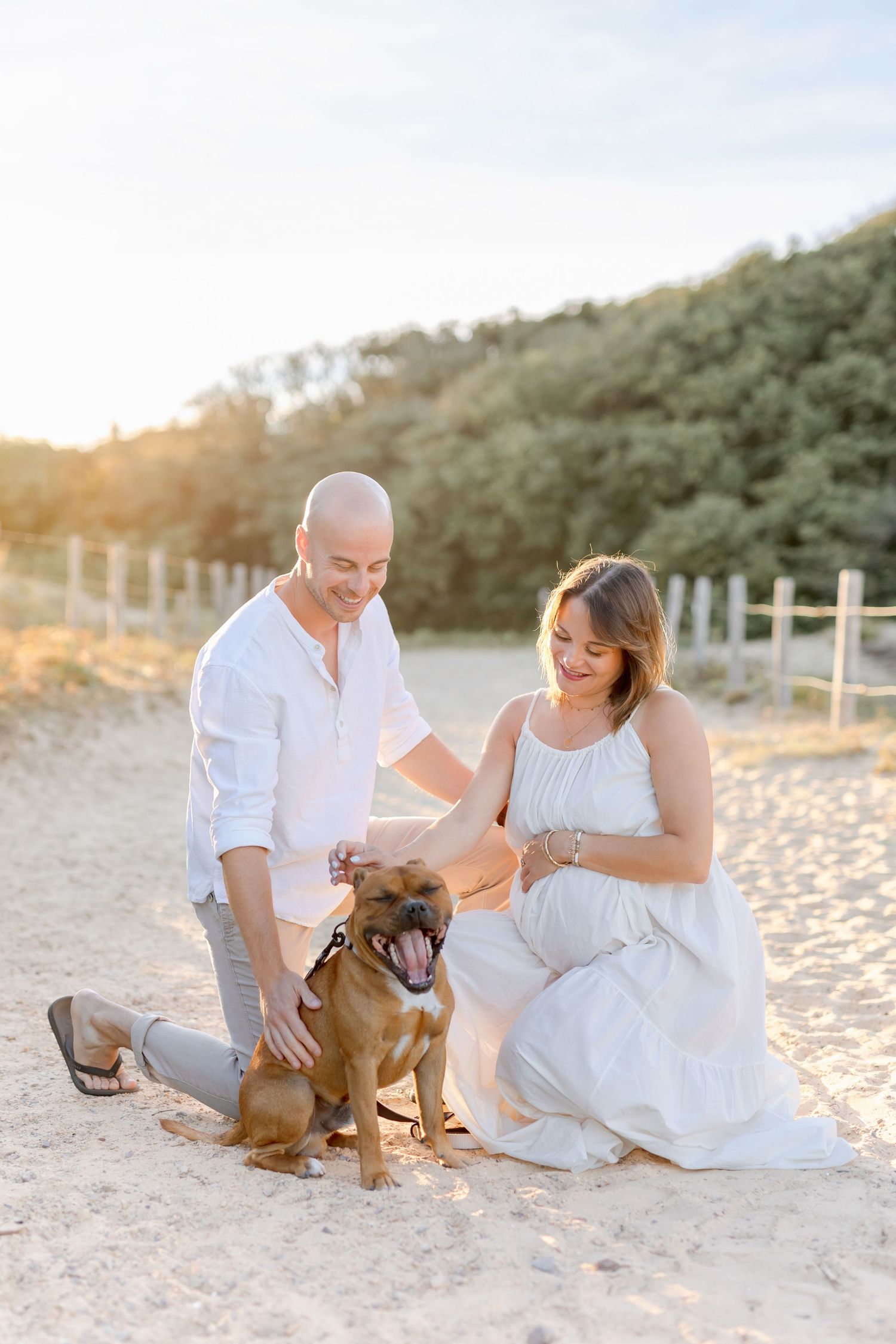 Couple and their dog enjoy tender moment during beach sunset photography session.