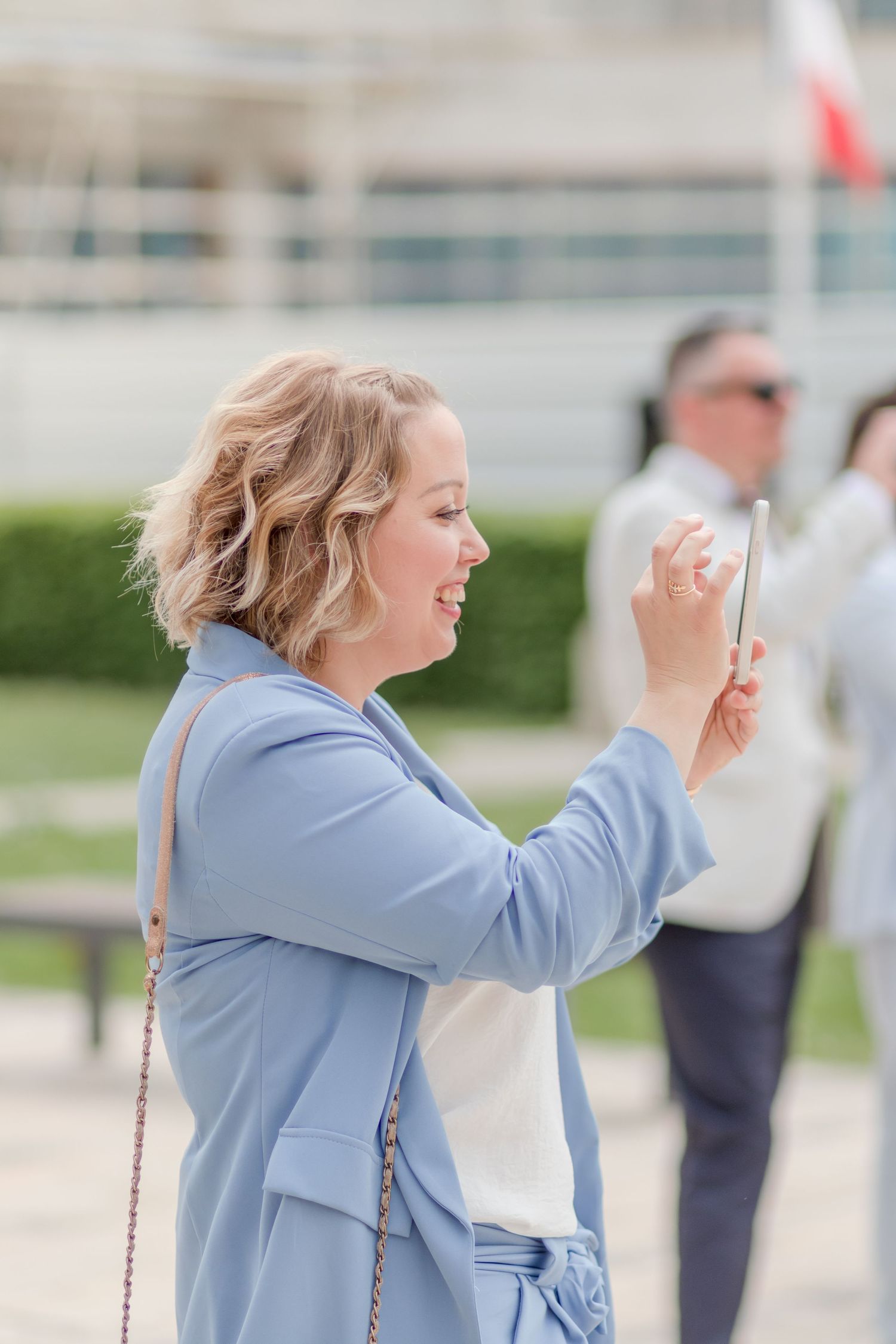 Woman in light blue blazer gestures excitedly during outdoor celebration.
