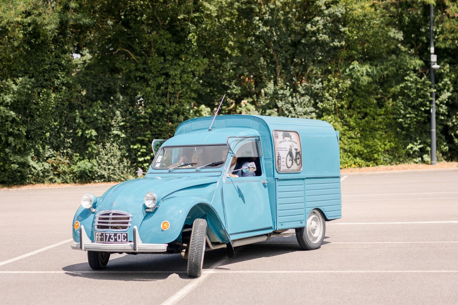 Vintage light blue Citroen 2CV van parked in sunny outdoor lot.