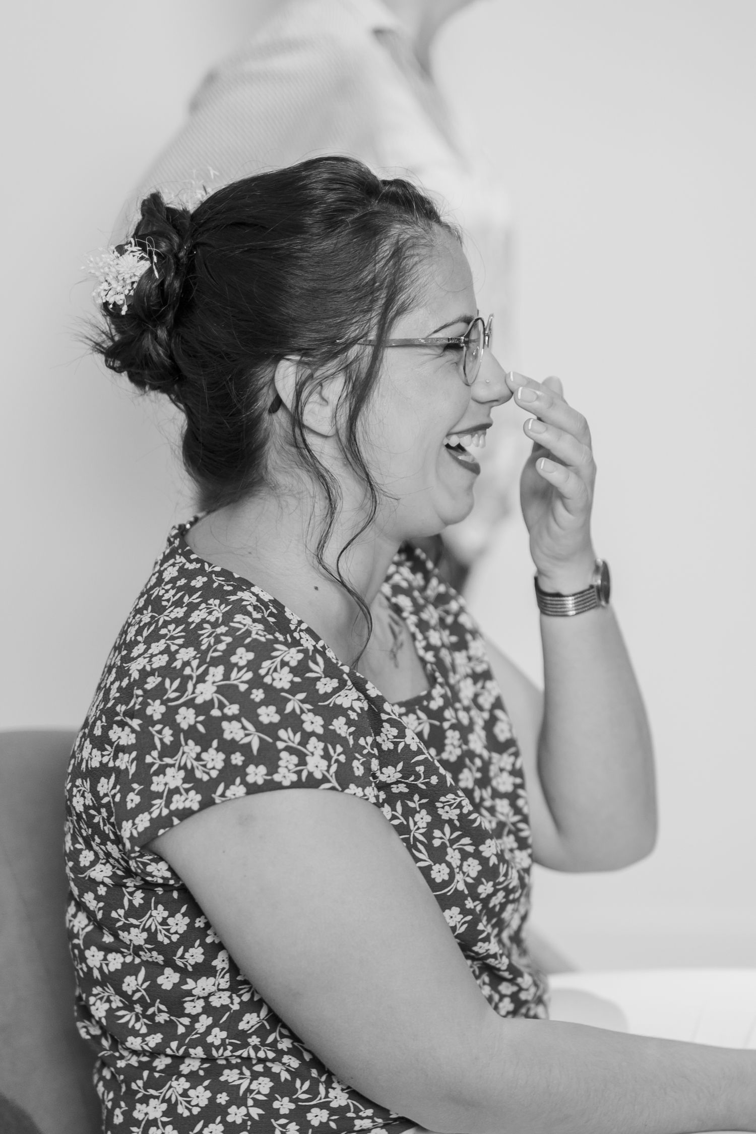 A candid black and white portrait of someone in a floral dress laughing joyfully.