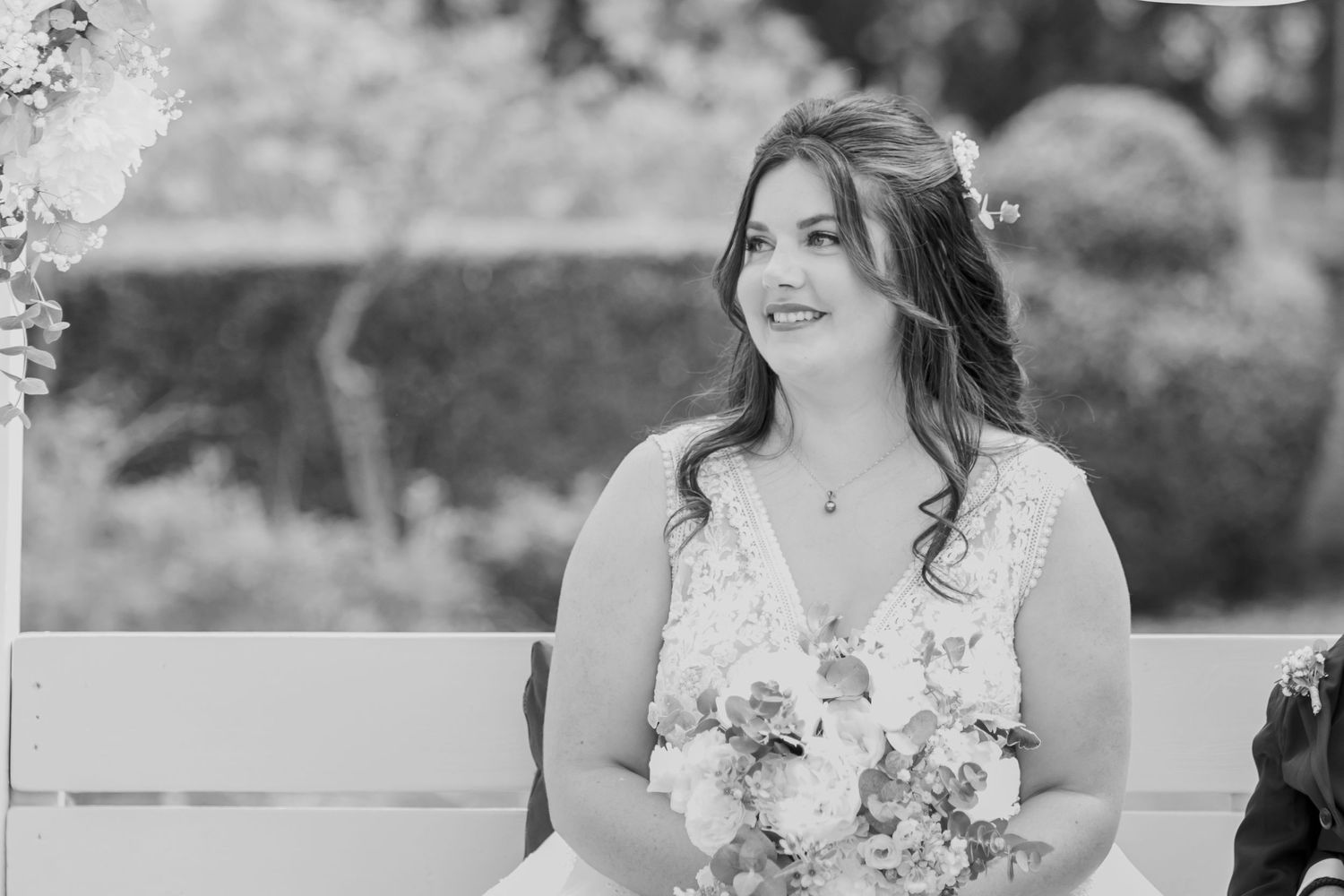 Black and white portrait of woman seated at outdoor wedding ceremony.