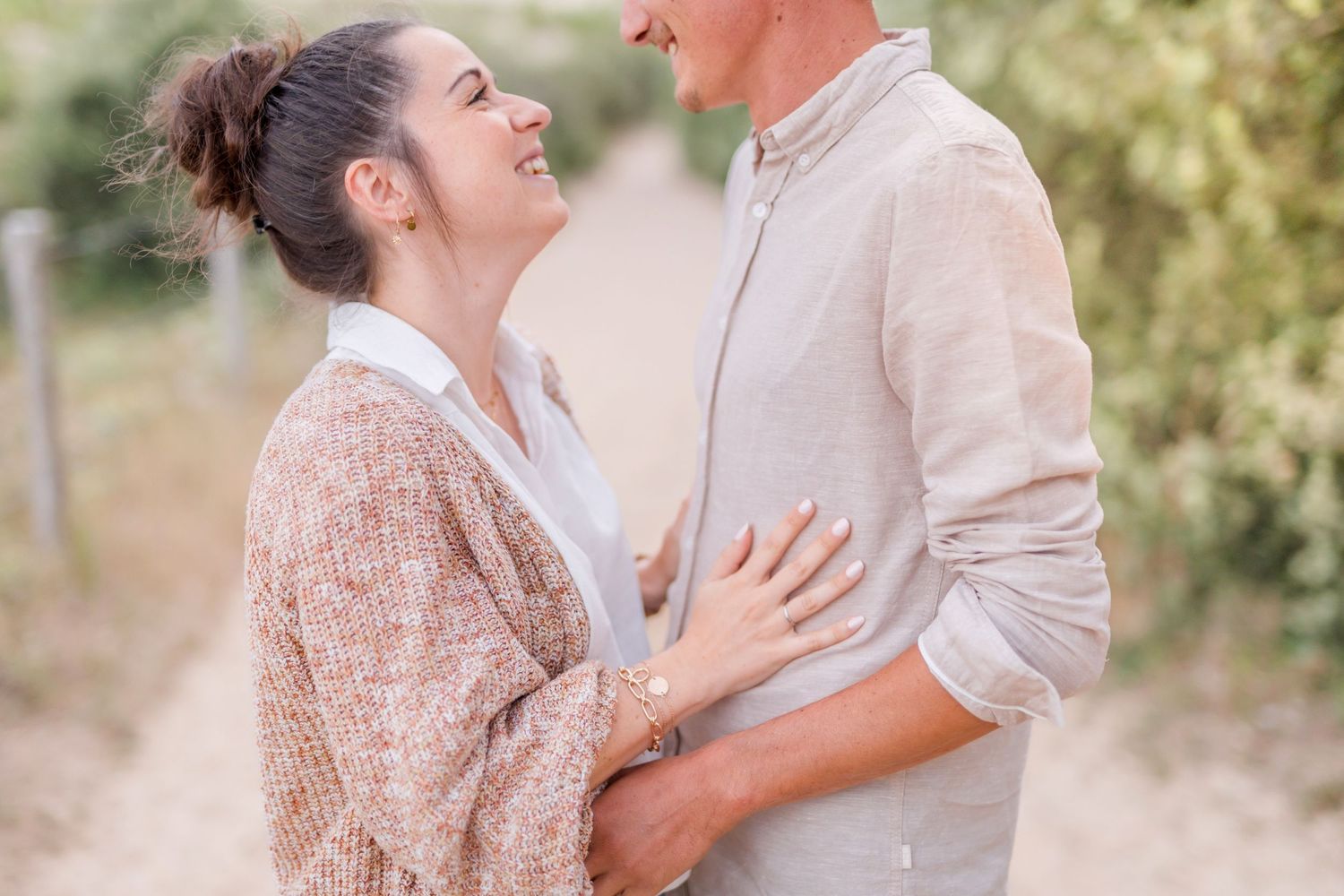 Couple sharing intimate moment on nature trail wearing light colored clothing.