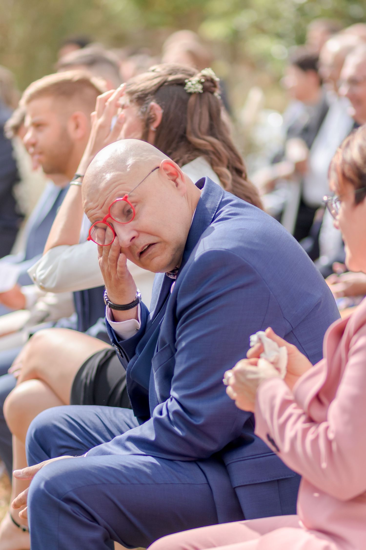 Wedding guests displaying emotional reactions during outdoor ceremony.